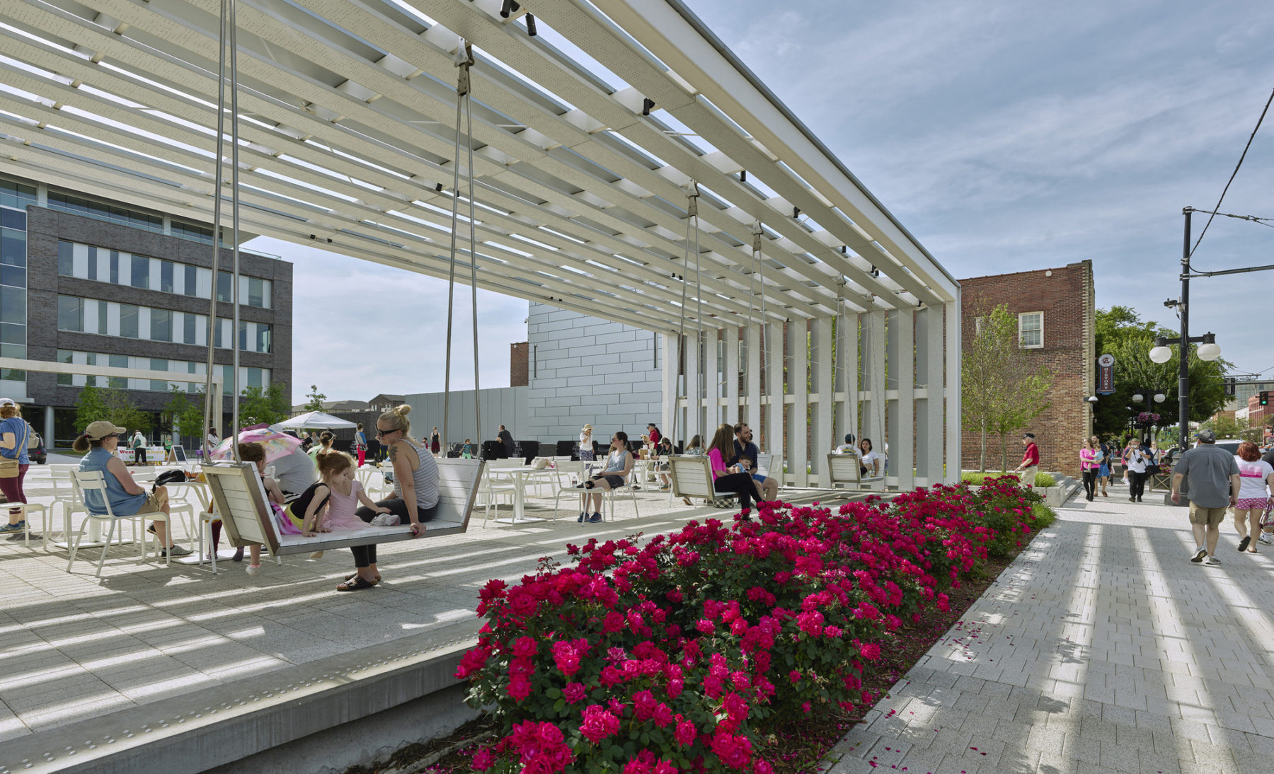 photo of built in swings on plaza red flowers line the sidewalk in the foreground