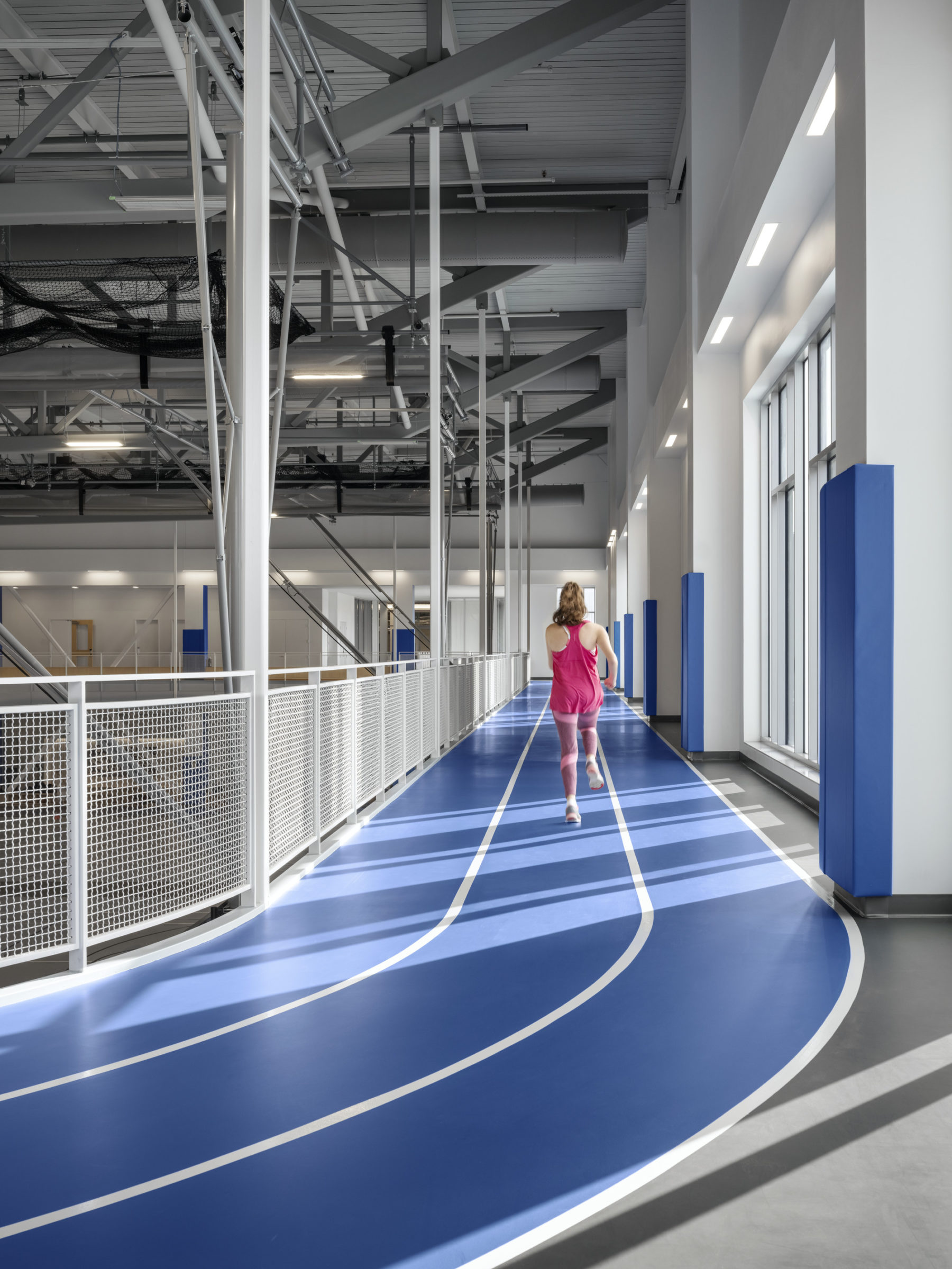 interior photo of elevated track. a woman in pink runs in the center lane.