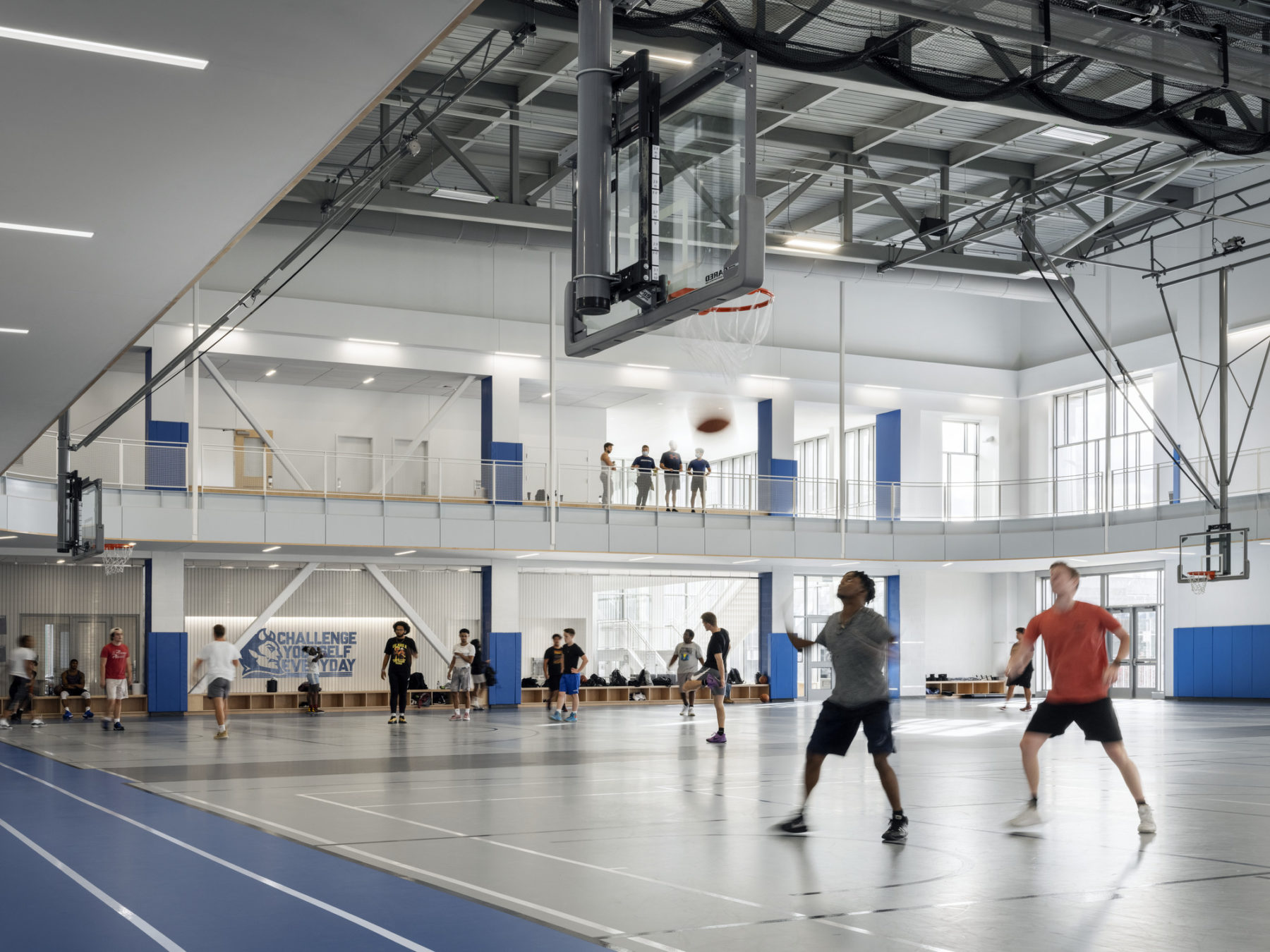 interior photo from edge of basketball court. two players stand beneath the basket