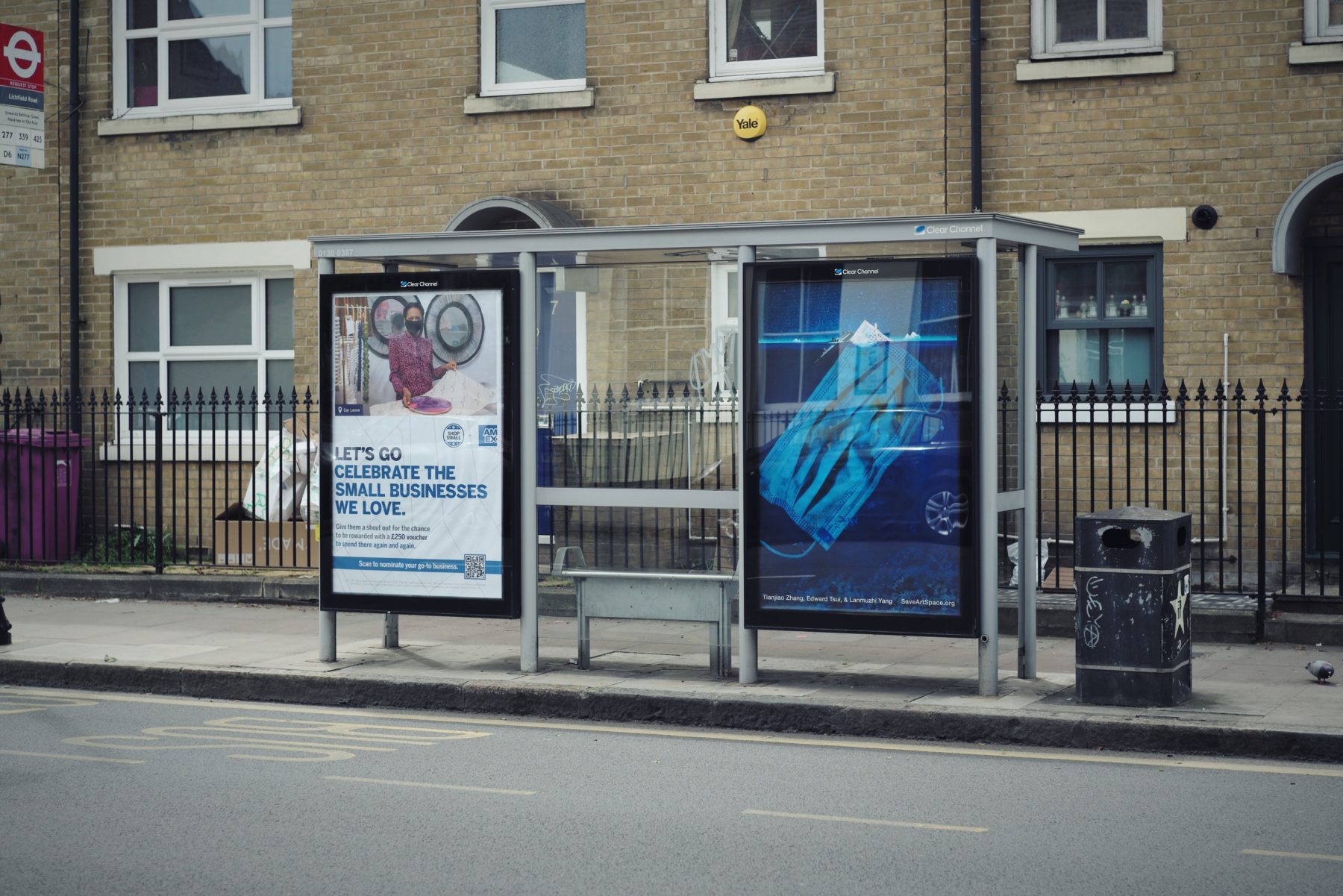 Photo of an ad at a bus stop. The ad is an image of a giant medical mask in the ocean, with its tip sticking out of the surface of the water like an iceberg.