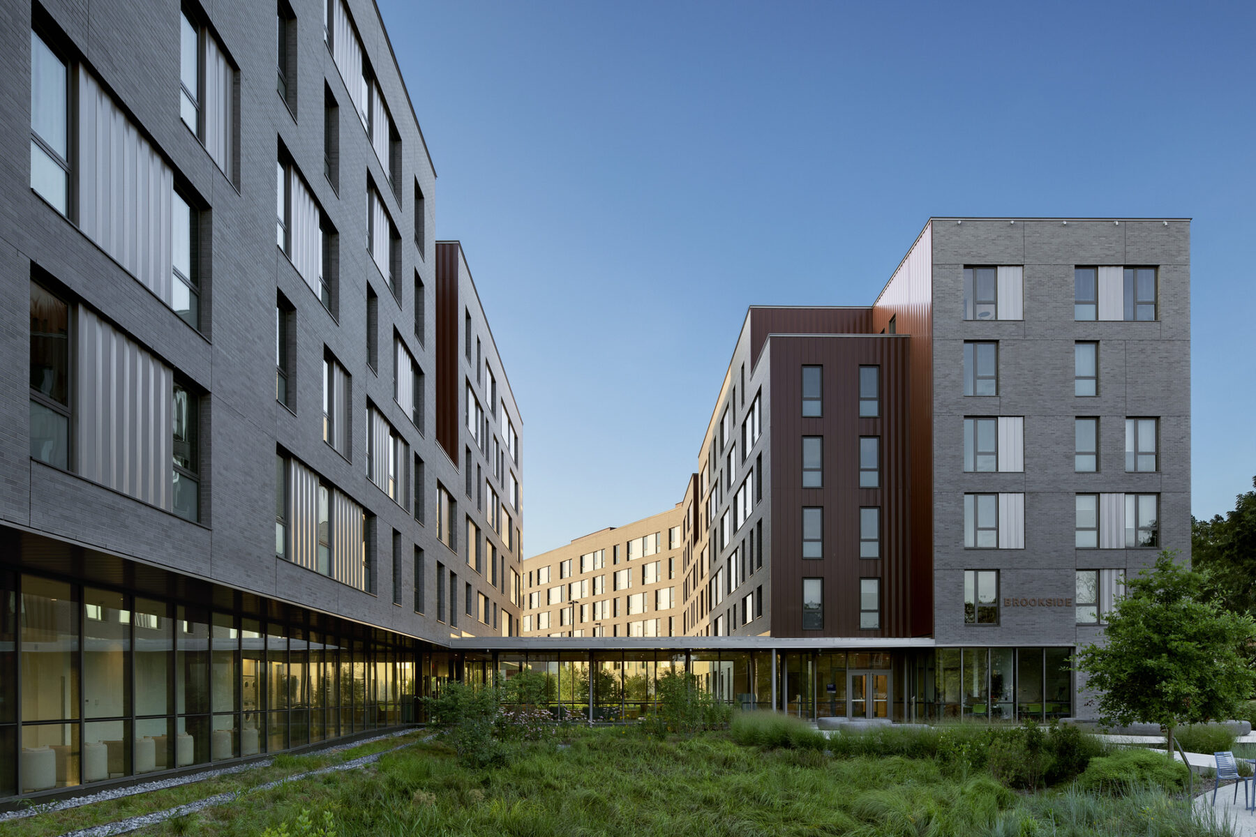 Late afternoon sunlight on the Brookside Apartments building with restored landscape in foreground