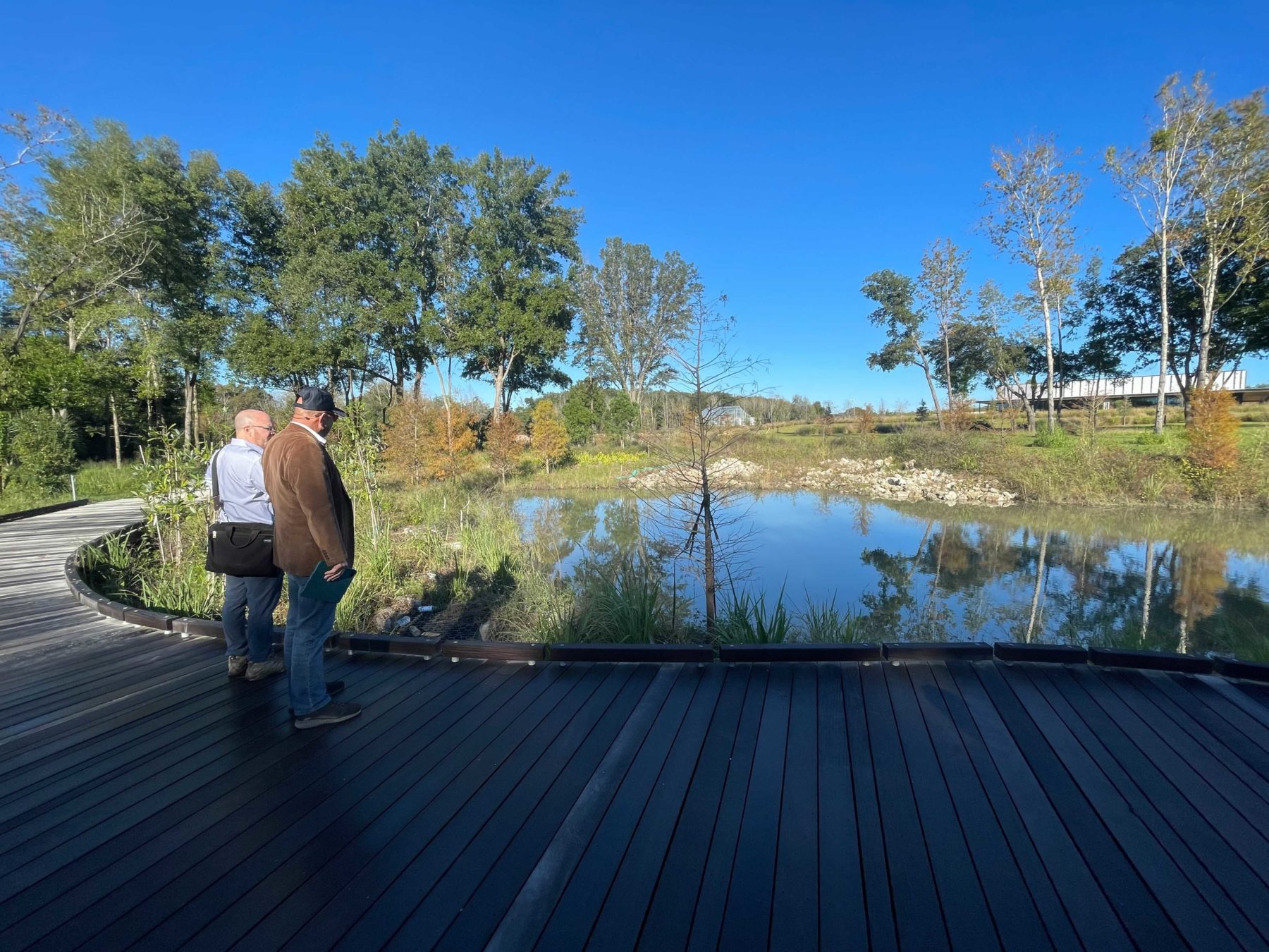 Two men standing on a new boardwalk looking out over a lagoon