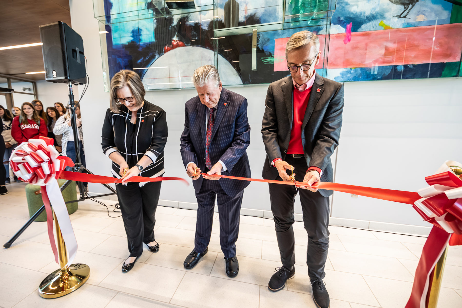 Three people cut a ribbon at the opening ceremony