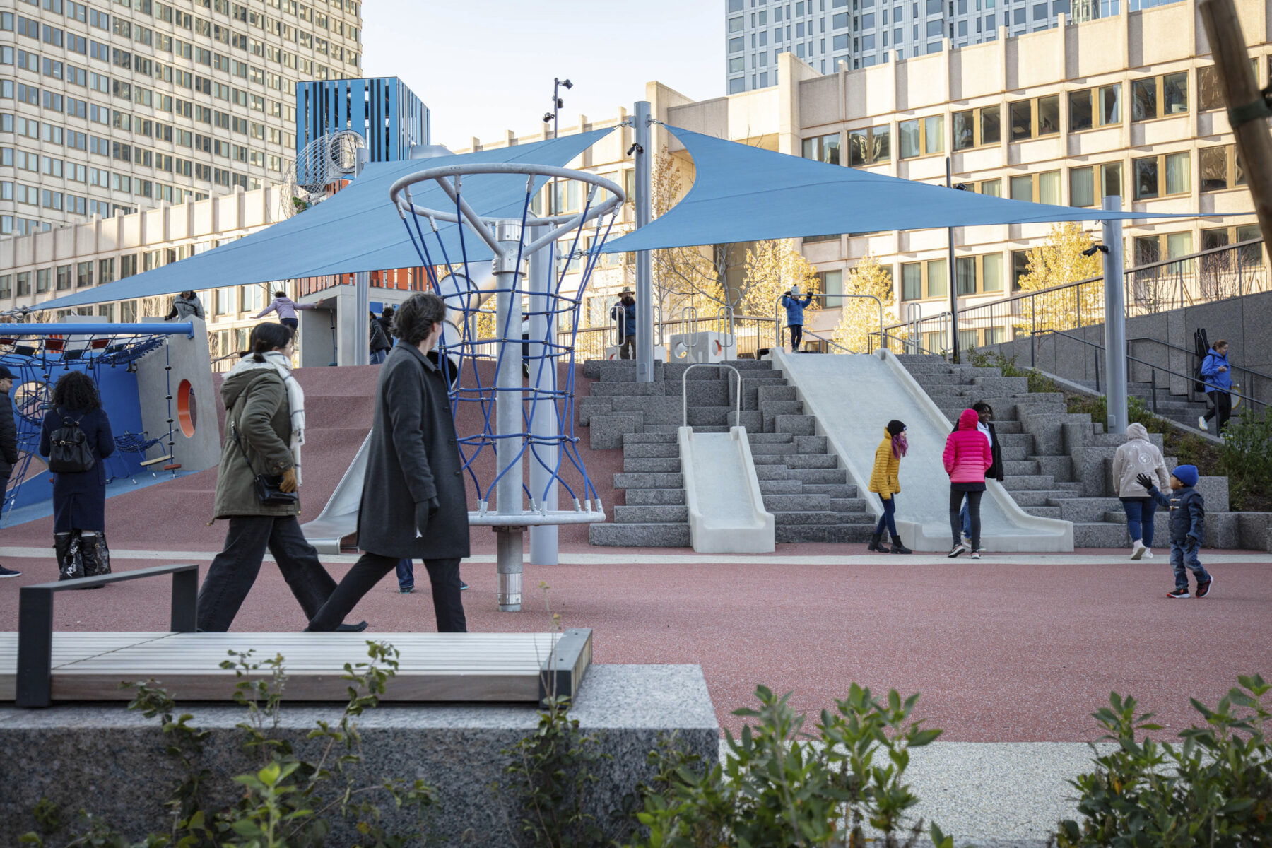 View looking up to play space on the plaza with pedestrians walking by