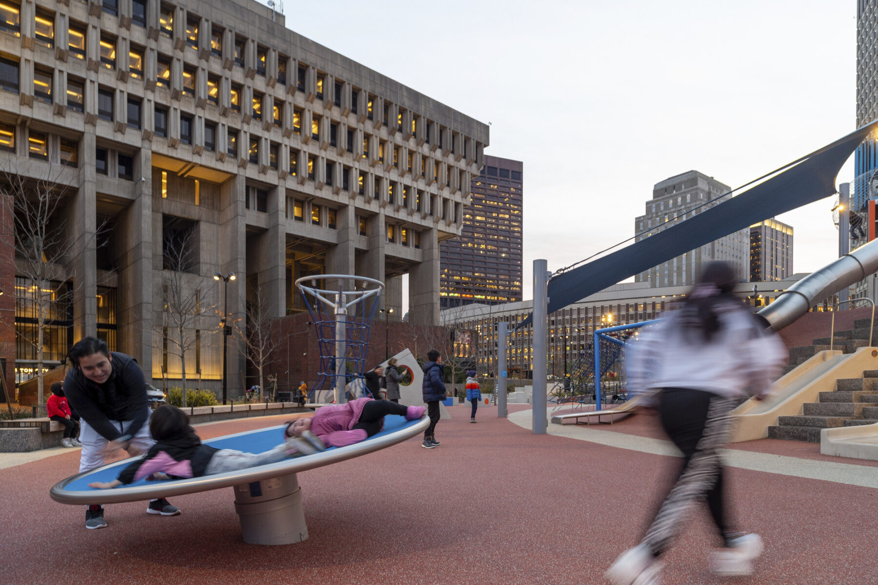Playground in front of the City Hall Plaza building with kids running and climbing on playscapes