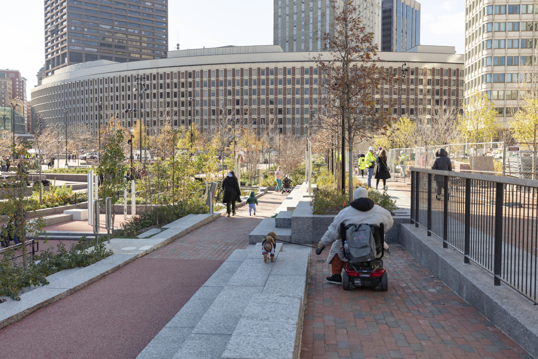 Person in wheelchair walking dog and using new accessible paths across the plaza