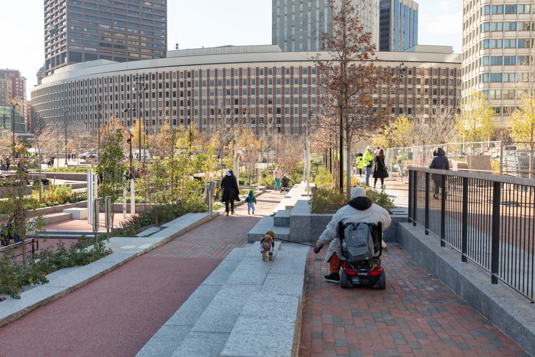 A woman using an electric wheel chair explores the plaza with her dog