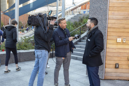 Photo of a news reporter and a cameraman talking to landscape architect Mauricio Gomez at Boston City Hall Plaza