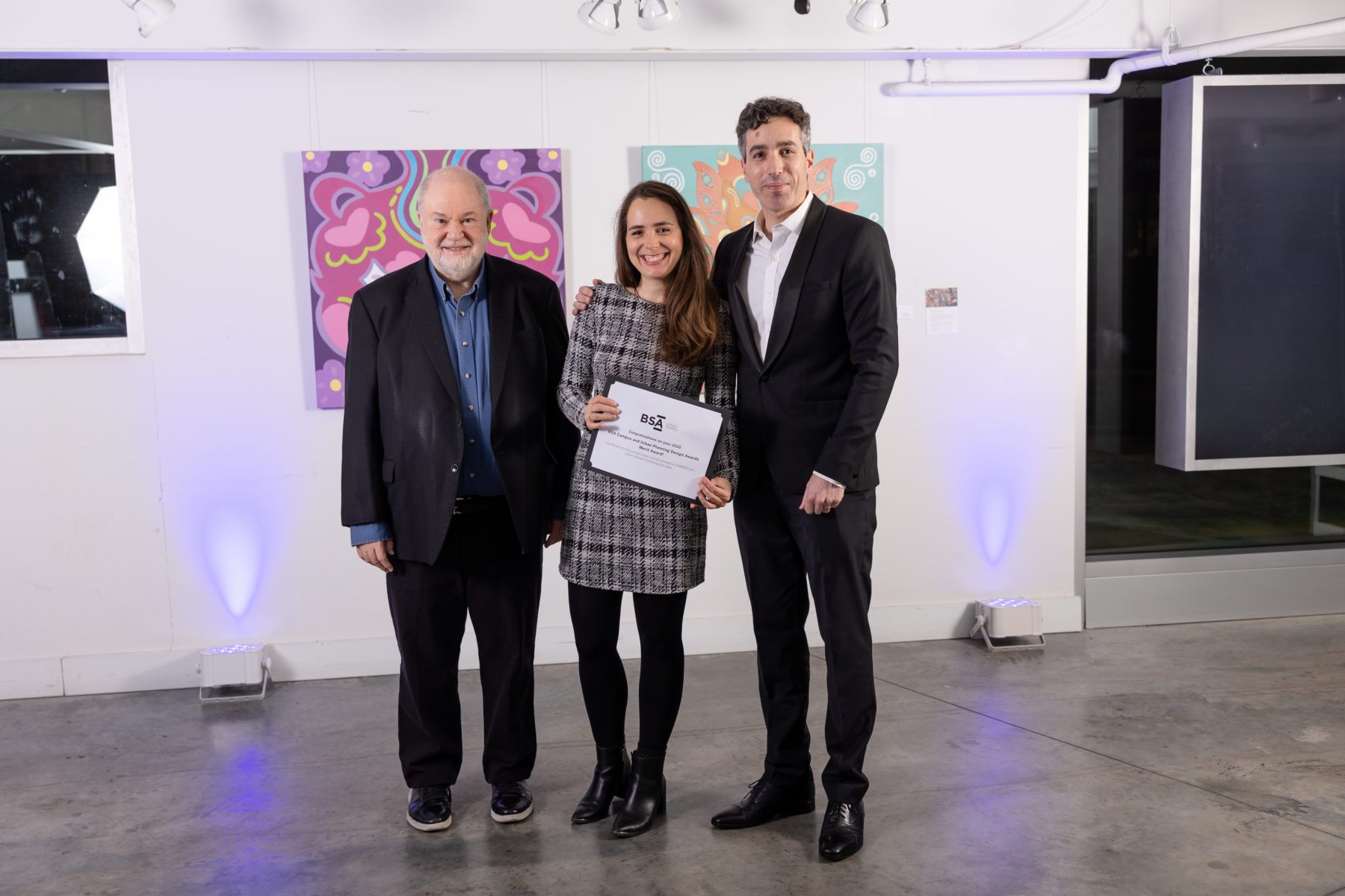 Three people dressed up smiling holding their award