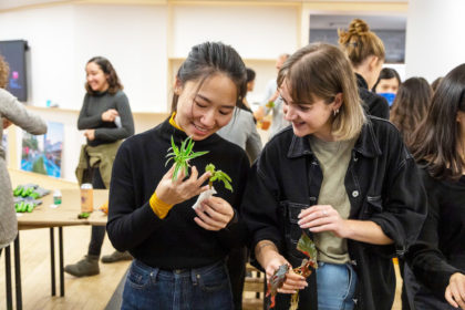 Photo of two people smiling and looking at a plant