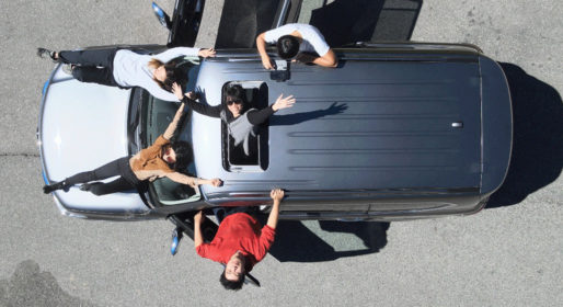 Top-down photo of a group of people hanging out of the windows of a car