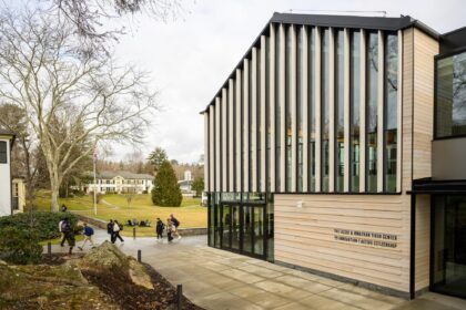 Photo of building exterior with campus context and pedestrians in the background