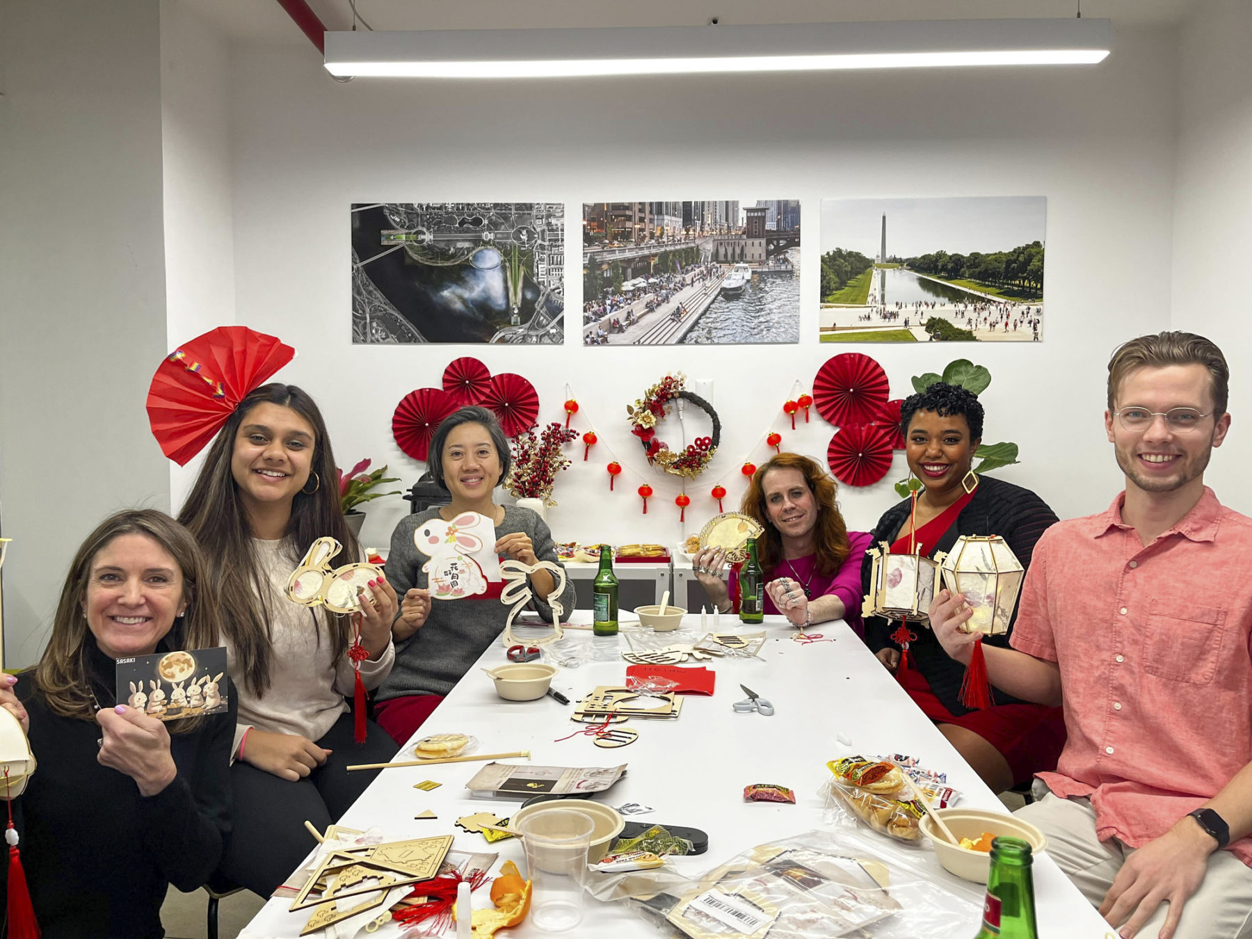 people smiling gathered around a table surrounded by red festive decorations