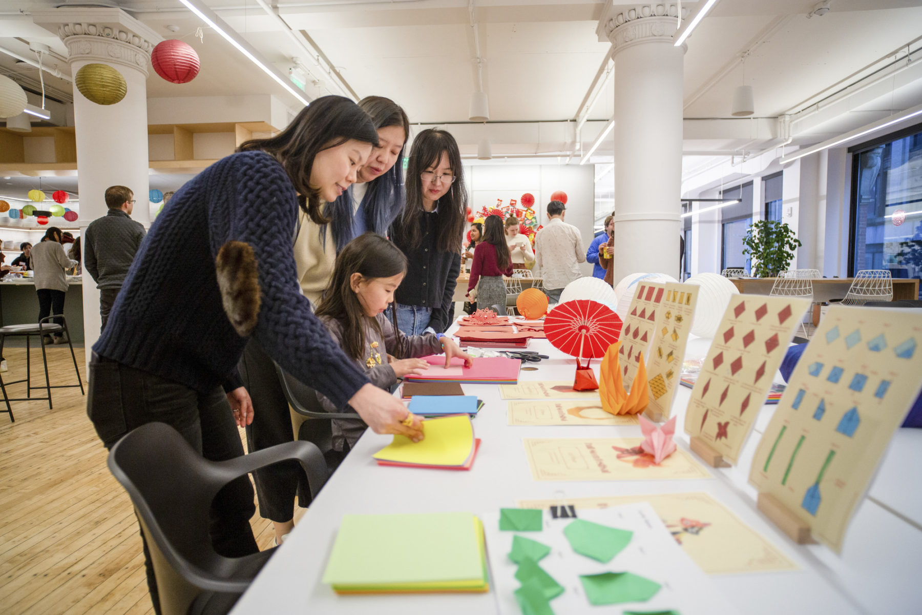 A mother shows her young daughter how to make origami at the origami station