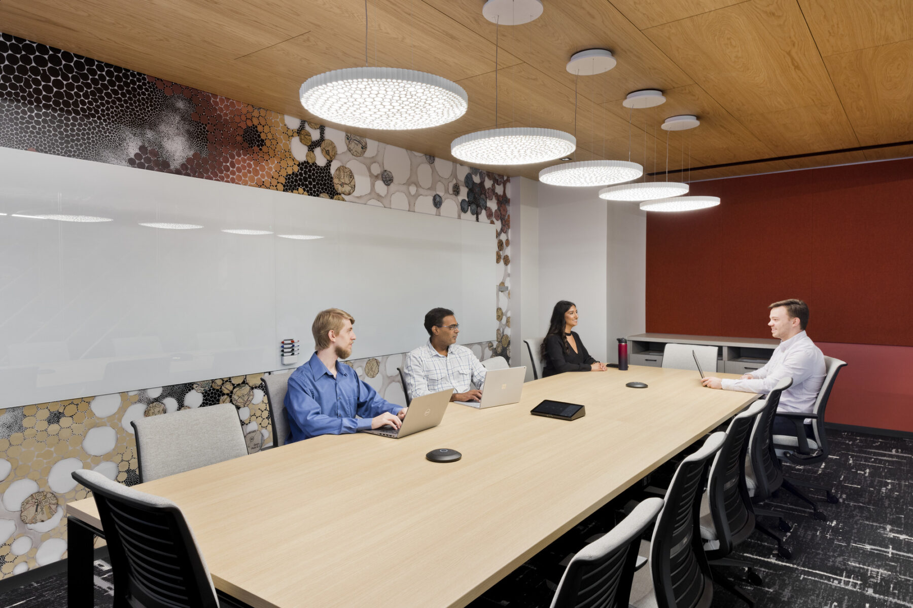 Conference room with large light fixtures above and a table and individuals seated together