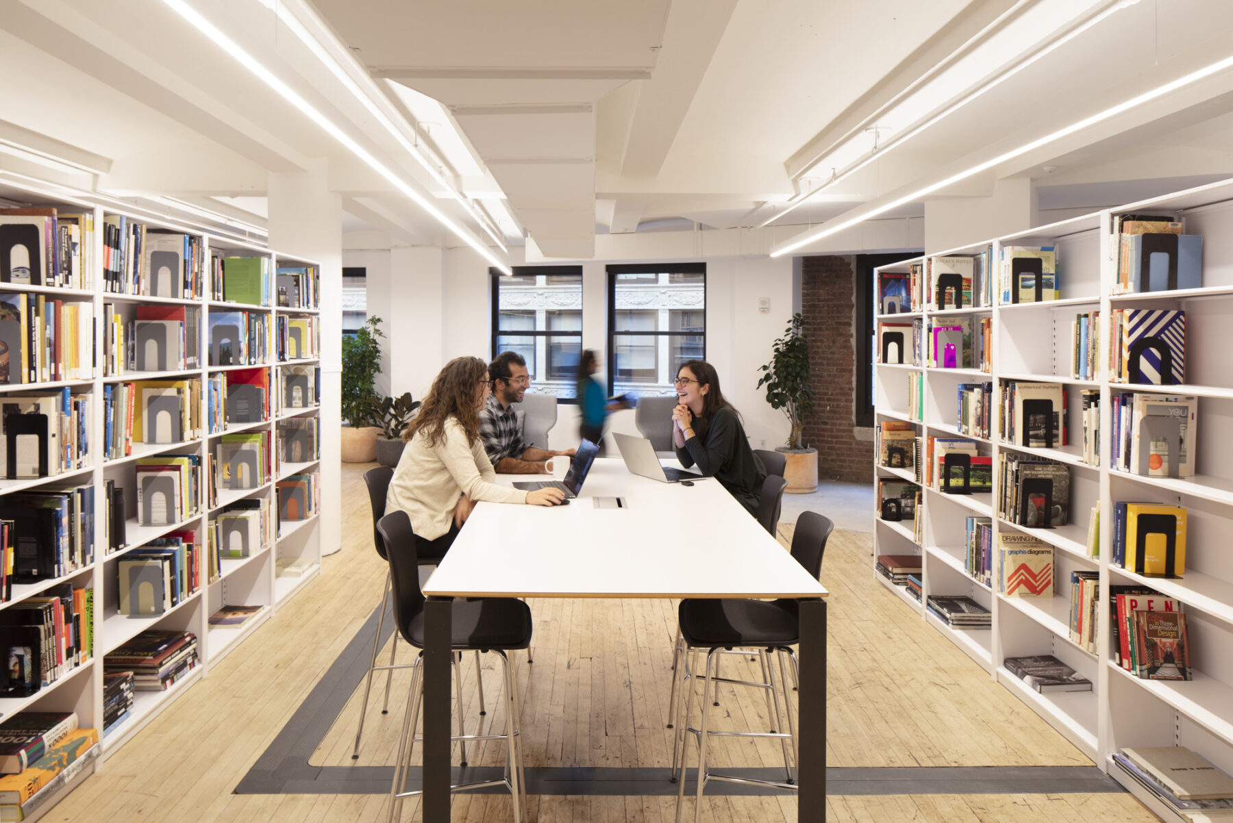 group around a table conversing in between library stacks