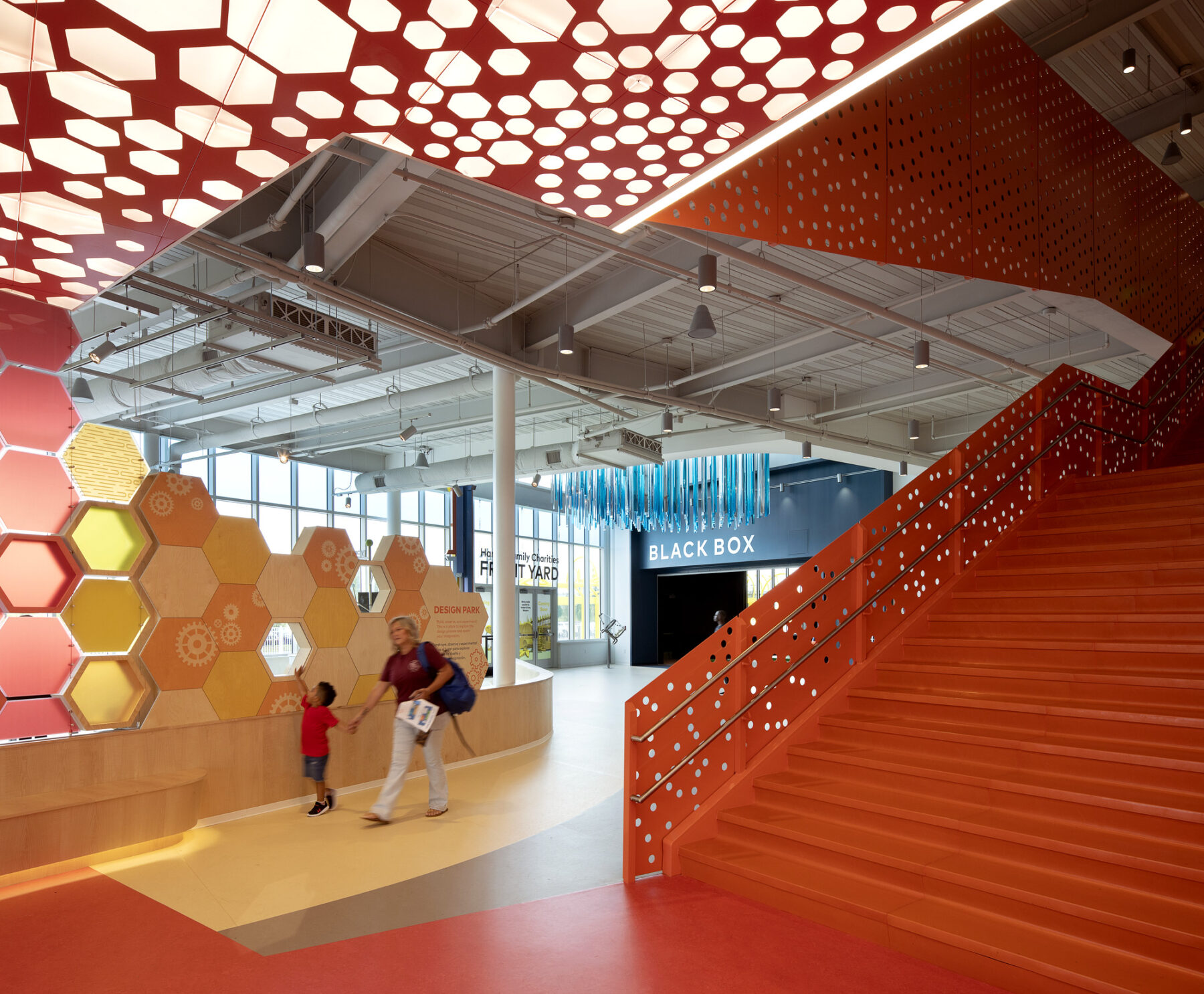Interior lobby of Children's Museum including bright red staircase and a perforated illuminated ceiling