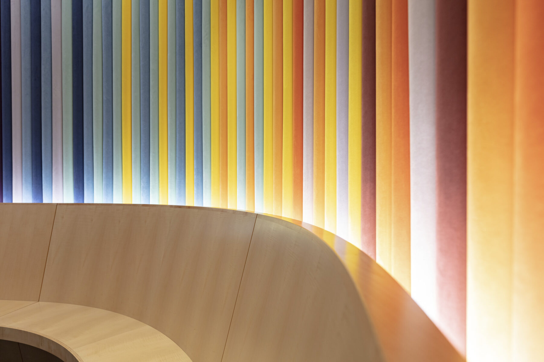 a close-up shot of the upholstered wall made up of vertical stripes ranging from blue to yellow, orange, and red.