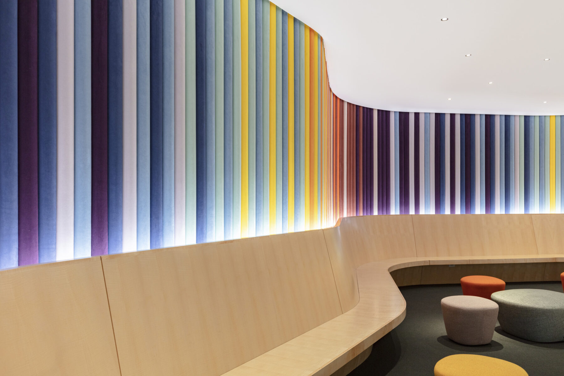 Lobby space with wrap around built-in bench and colorfully upholstered wall