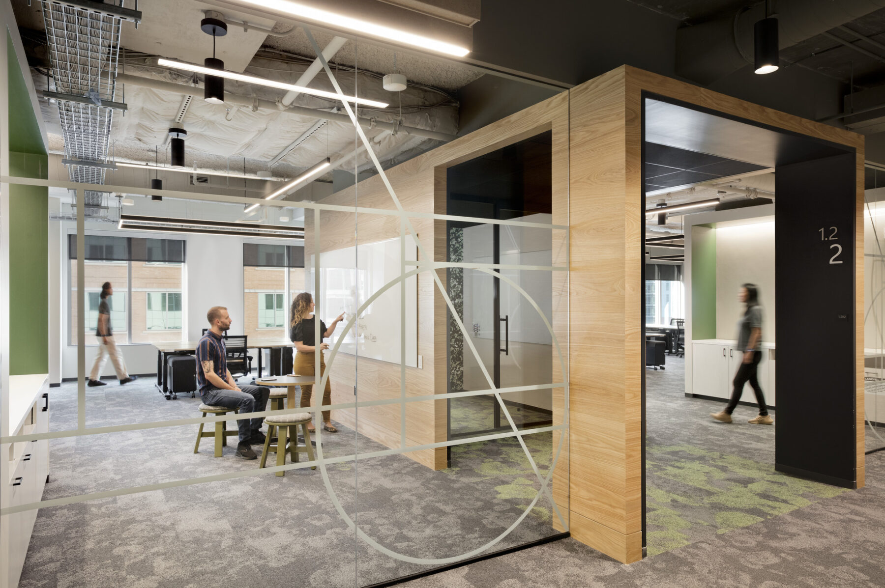 Team neighborhood area with open office space and two individuals meeting with a whiteboard
