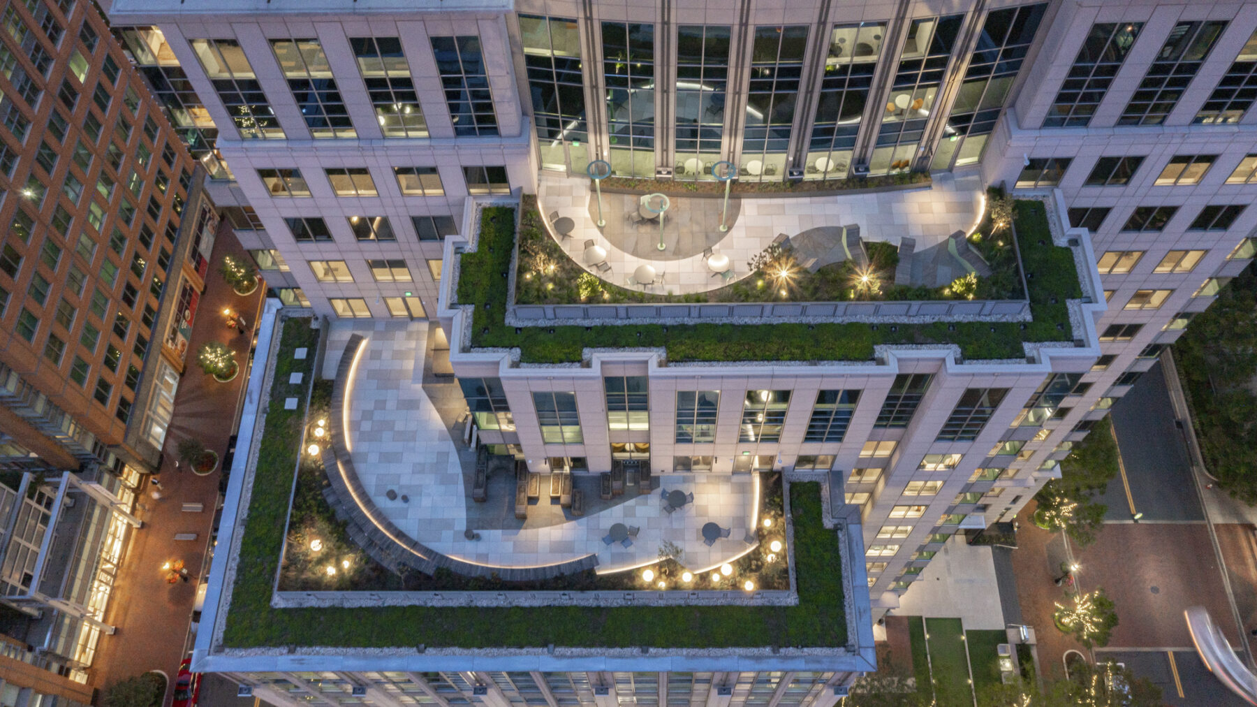 Aerial view of the building exterior at dusk showing the roof terraces with custom lighting