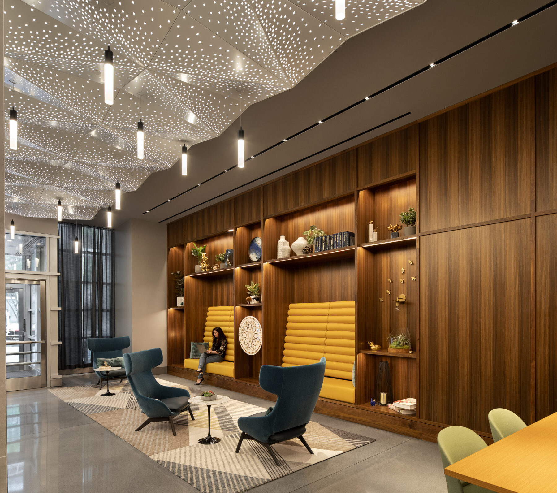 photograph of interior lobby space with backlit perforated ceilings, a millwork with curated decorations, and custom furniture