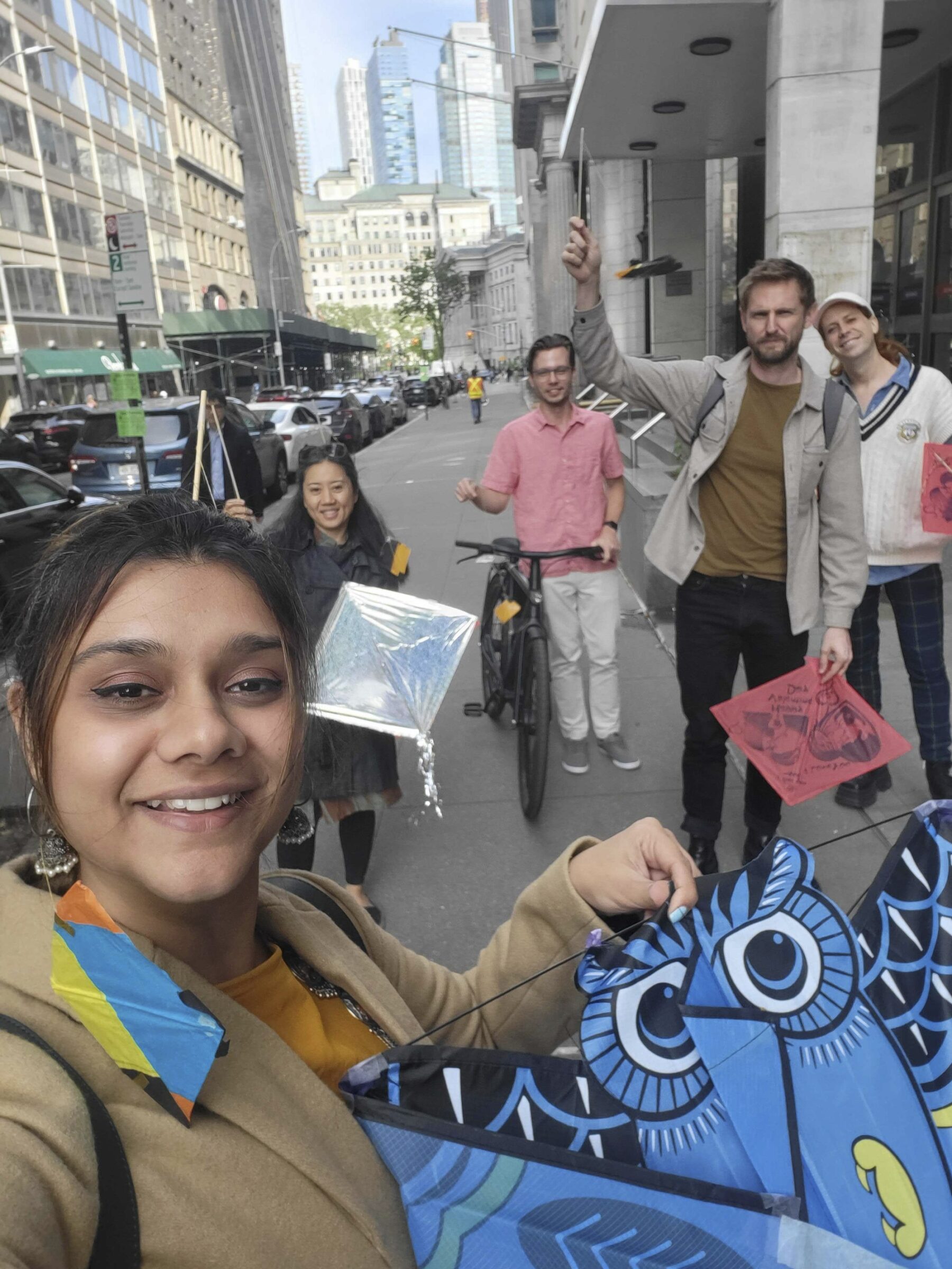 a selfie of a small group of people walking down the street holding kites