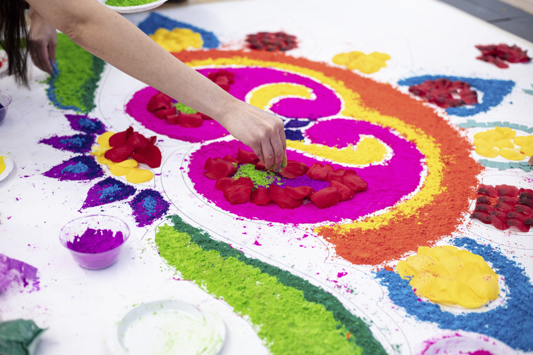 close-up photo of someone sprinkling colored powder to make rangoli