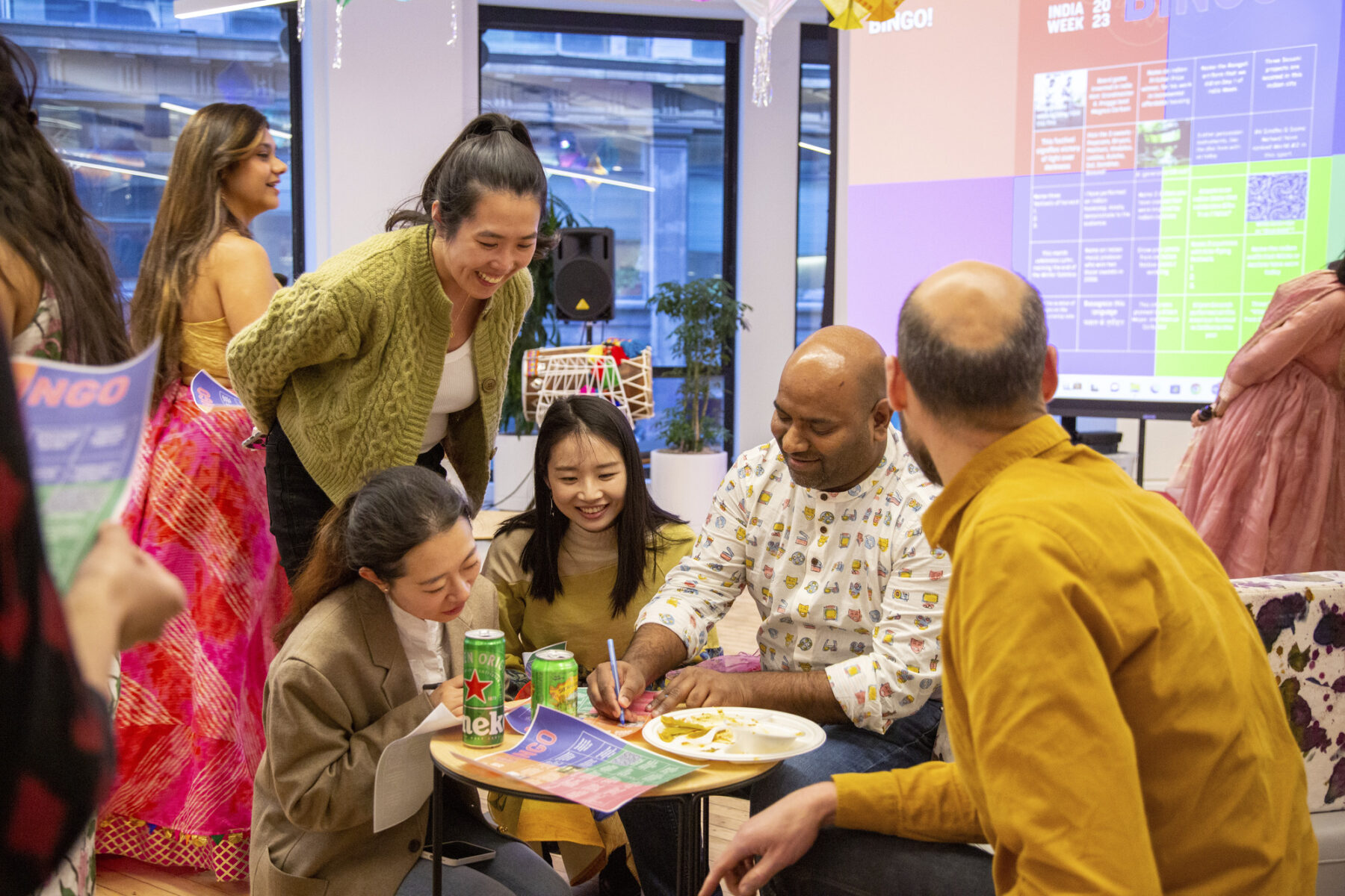 a group of people smiling and looking down at bingo sheets