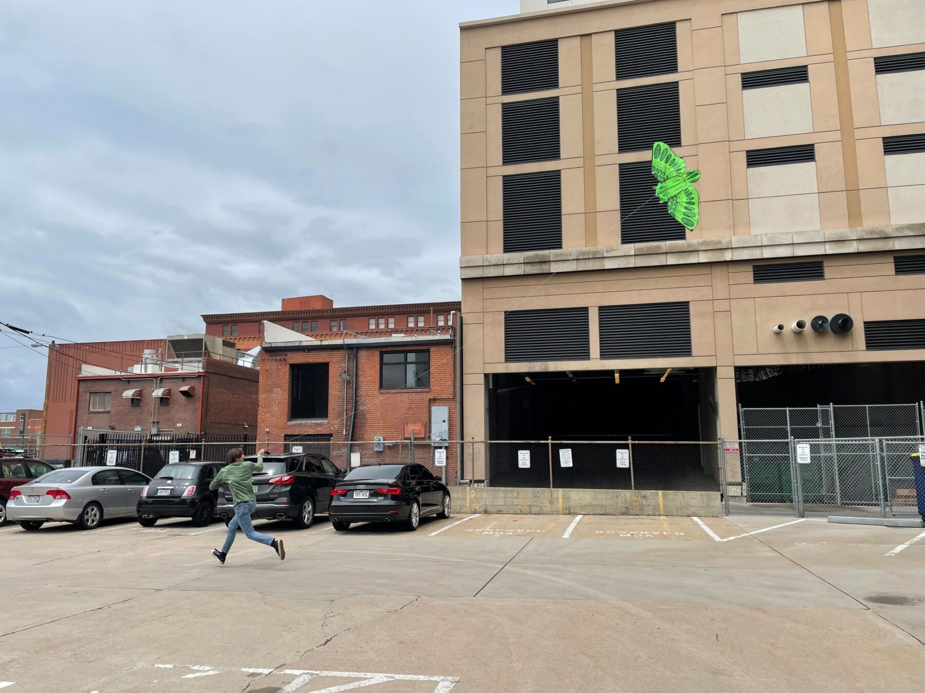 photo of someone running and flying a kite in a parking lot