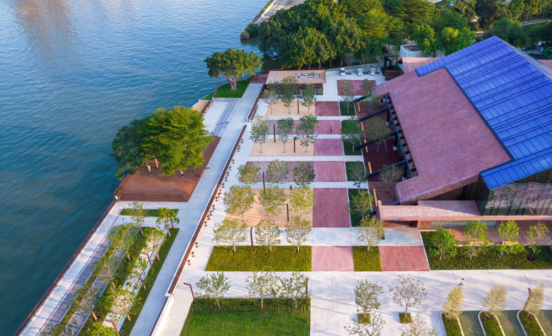 Aerial photograph over the Bai'etan Exhibition Center with riverfront and groupings of trees growing in a gridded, paved waterfront