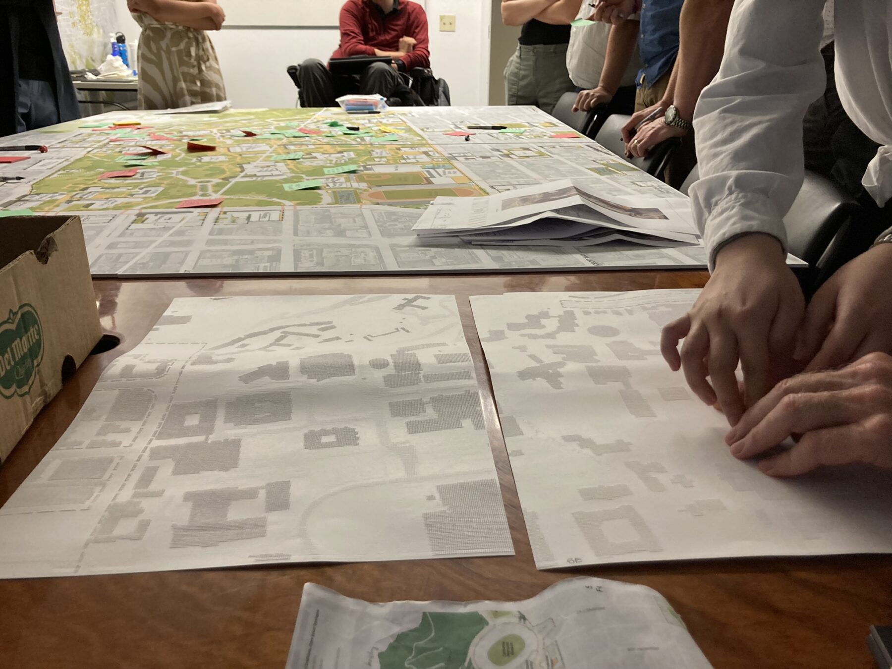 someone reading a plan translated into braille that is laid out on a table