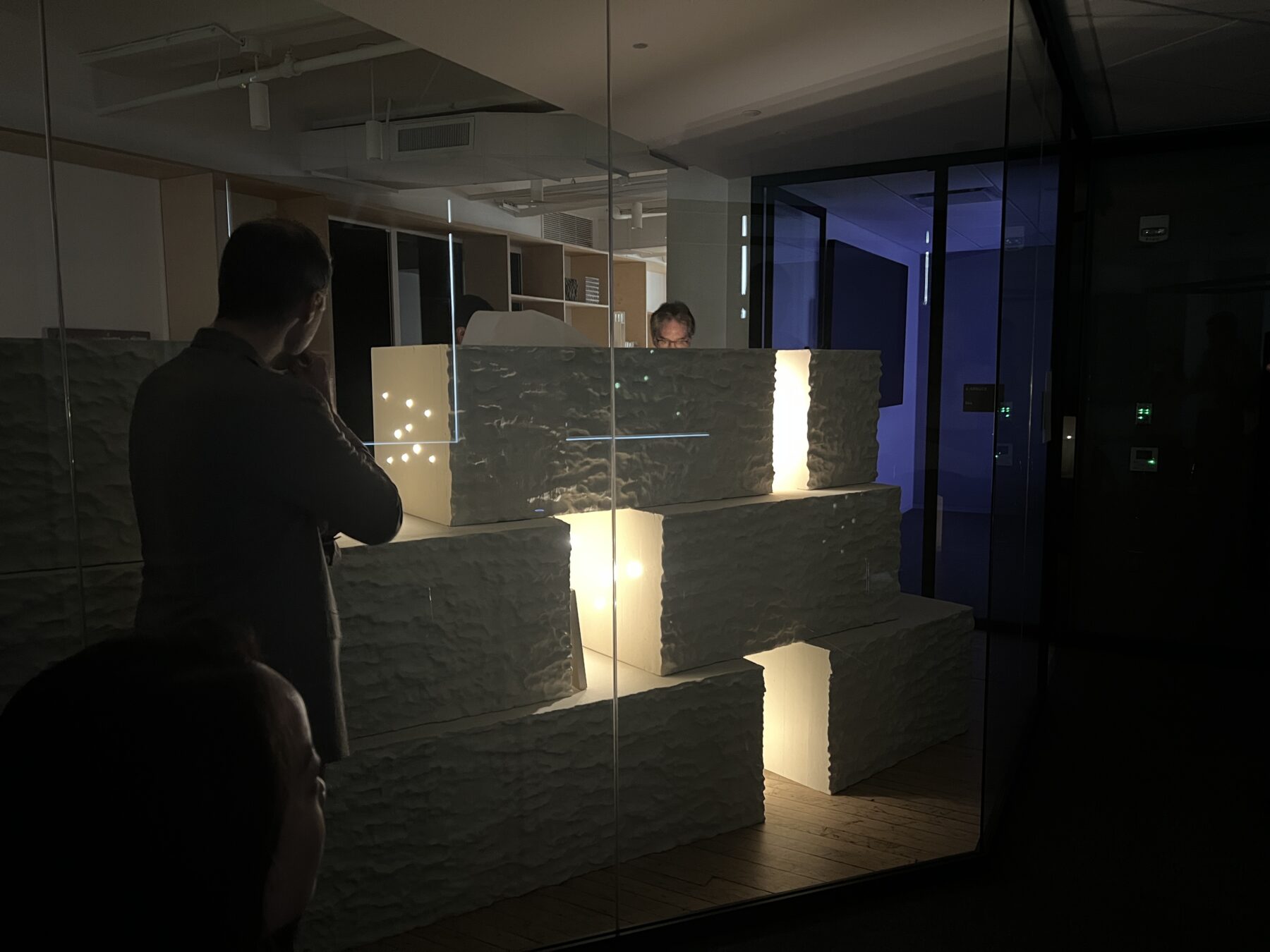 People in a dark room interacting with a mockup of white blocks stacked on top of each other and lit from within