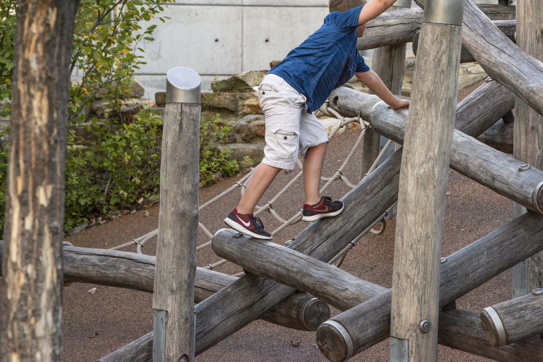 A child balances on a wooden play structure