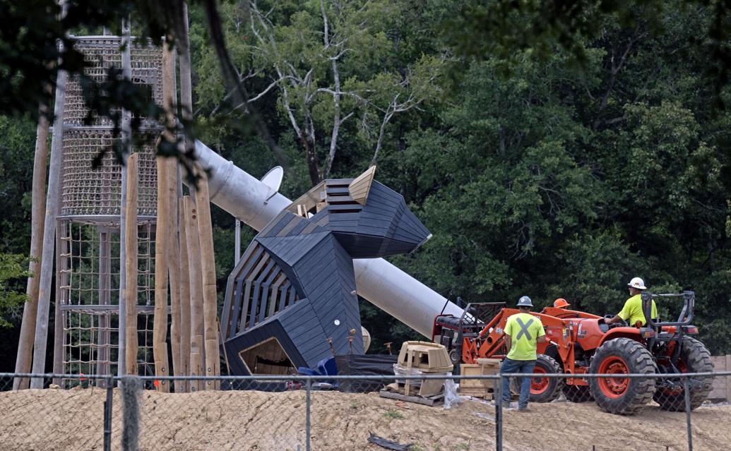Construction workers install a large bear on a playground