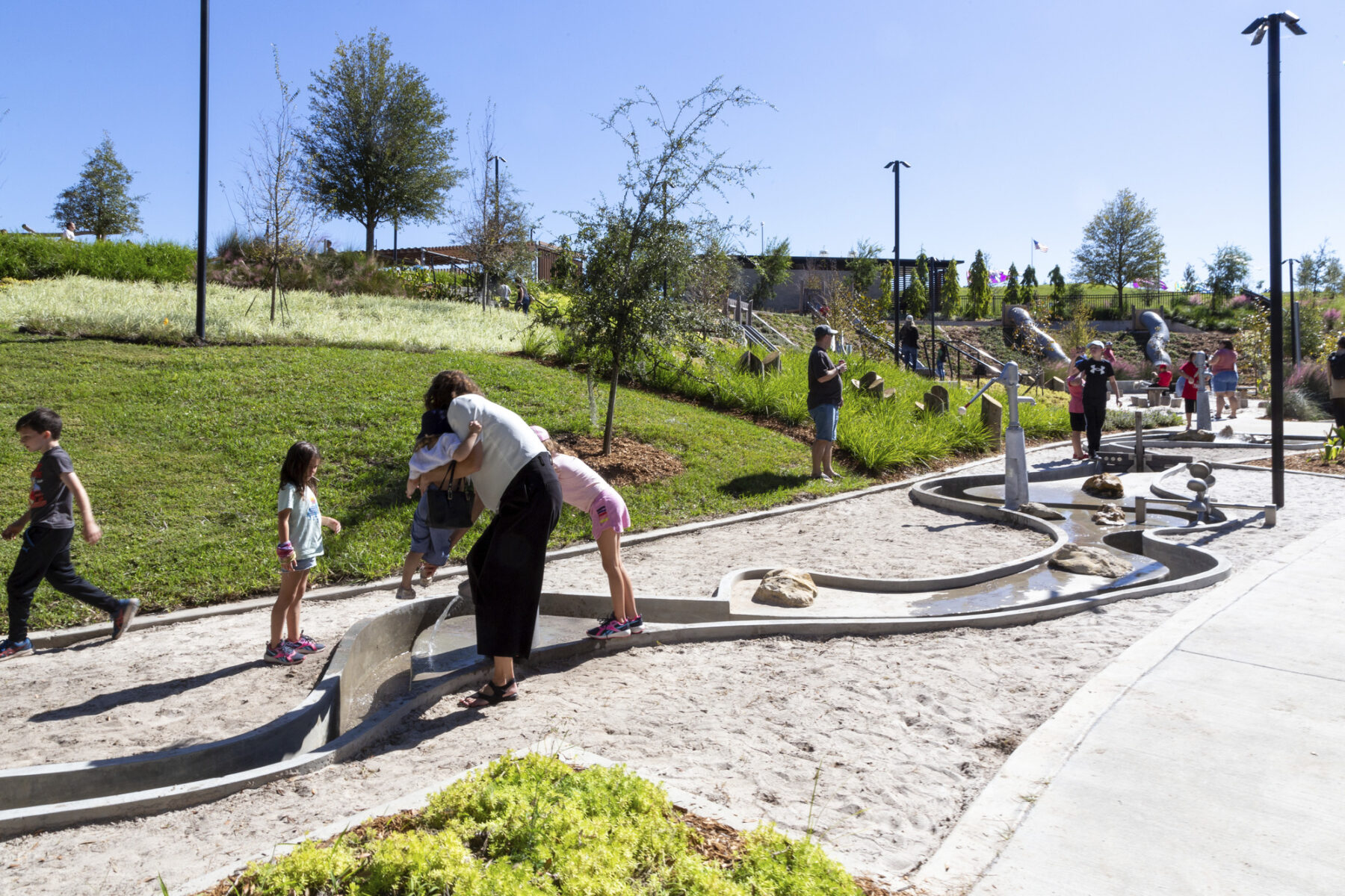 Mother and two children splashing in water feature at playground