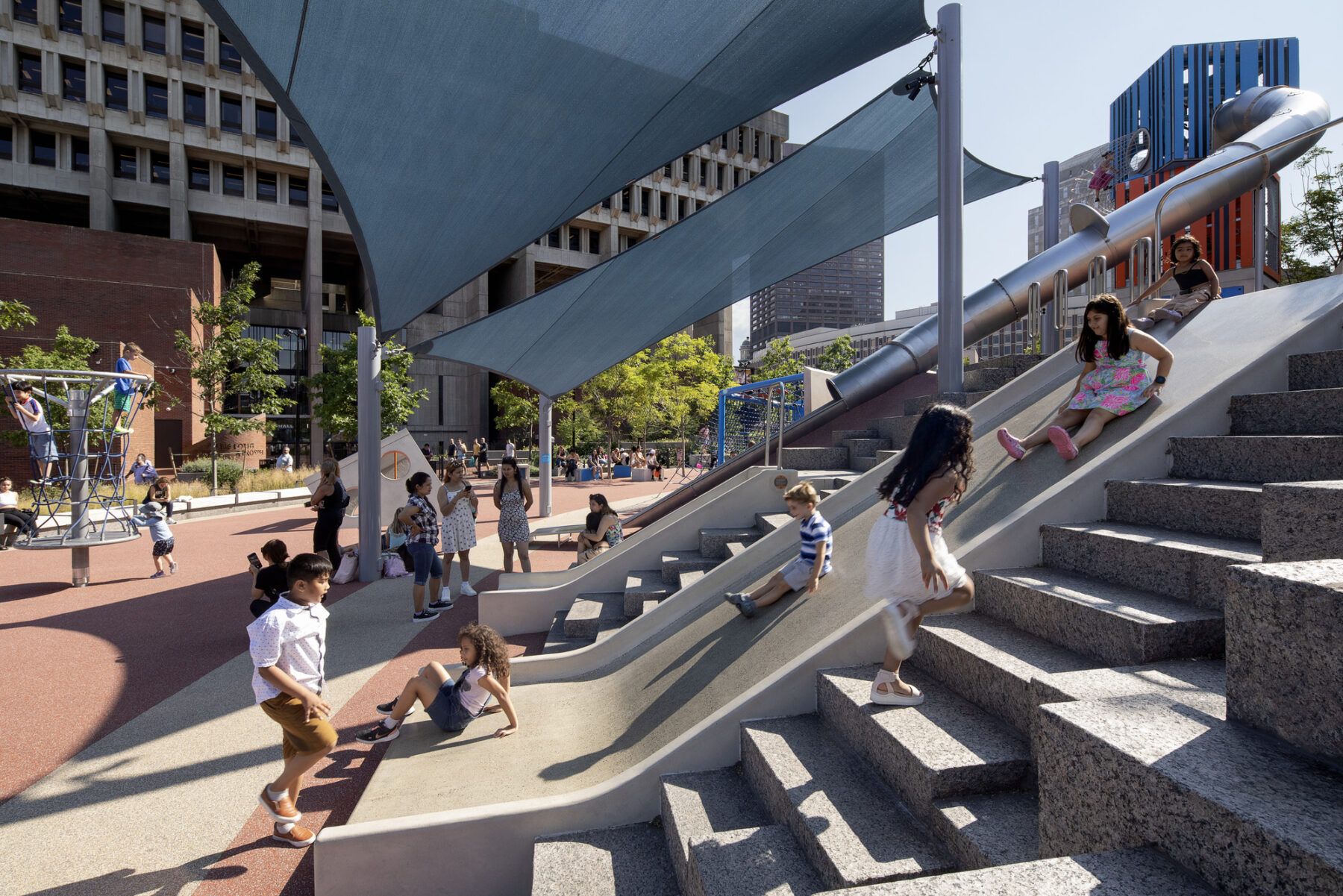 Afternoon photo--under a canopy, children scoot down slides and scramble up steps to do it again