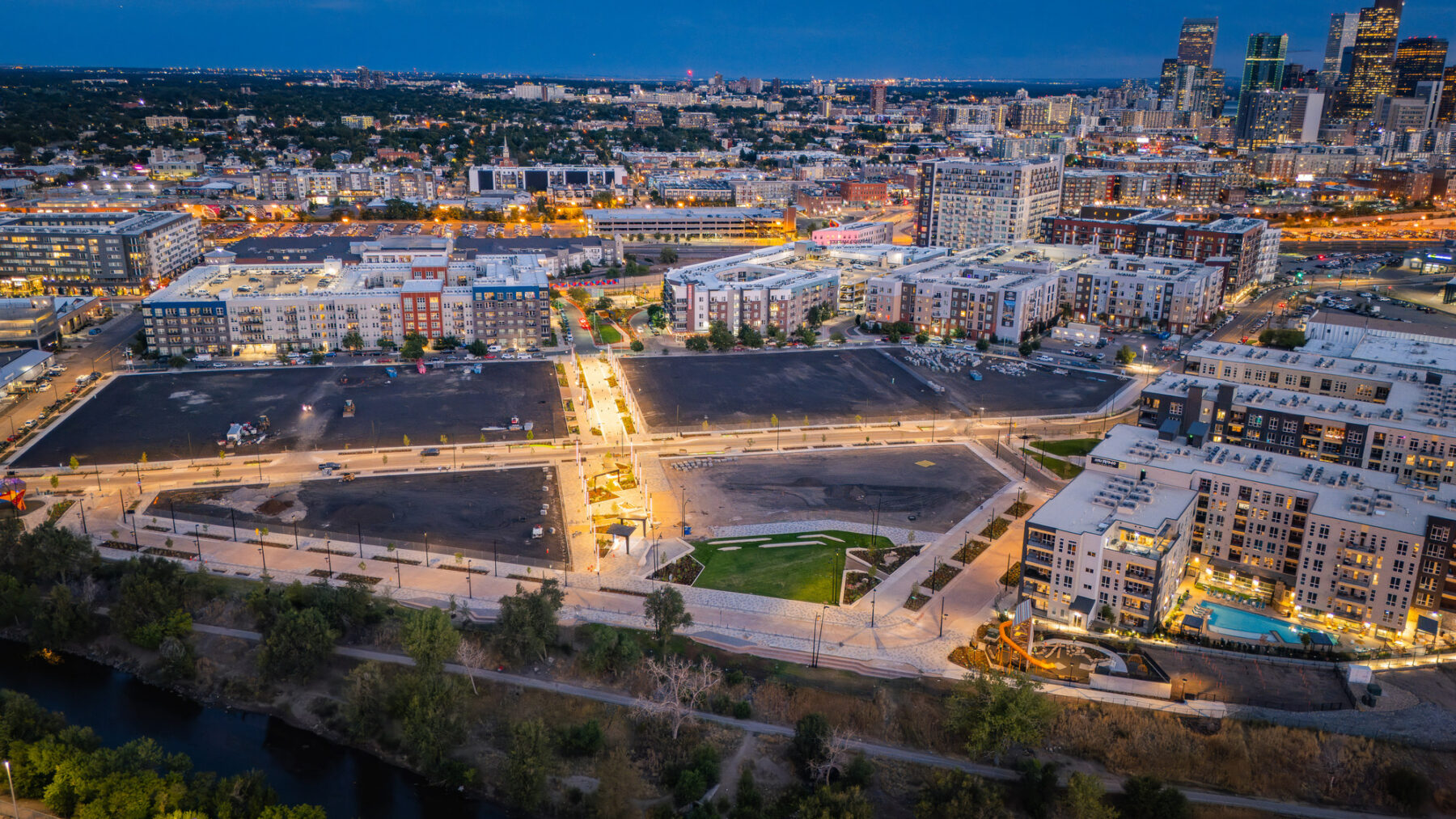 Aerial photo over the site at night with lights glowing in the completed public realm and surrounding city buildings