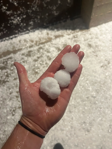wet hand holding three balls of ice, roughly golf ball sized