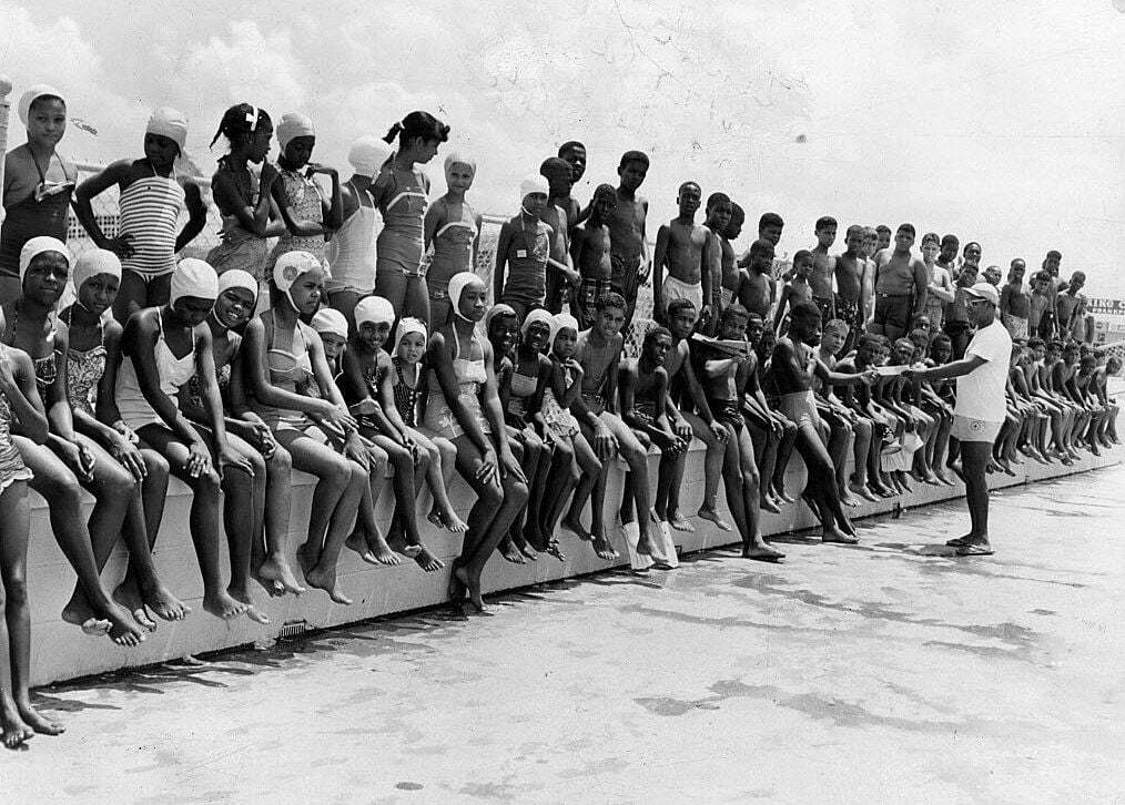 black and white photograph of residents posing along beach wall