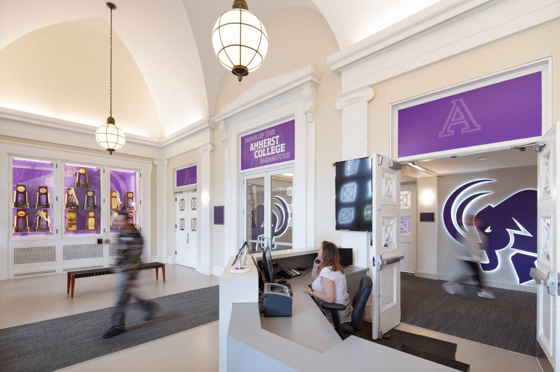 photograph of renovated interior entry space featuring reception desk and custom graphics above restored glass doors