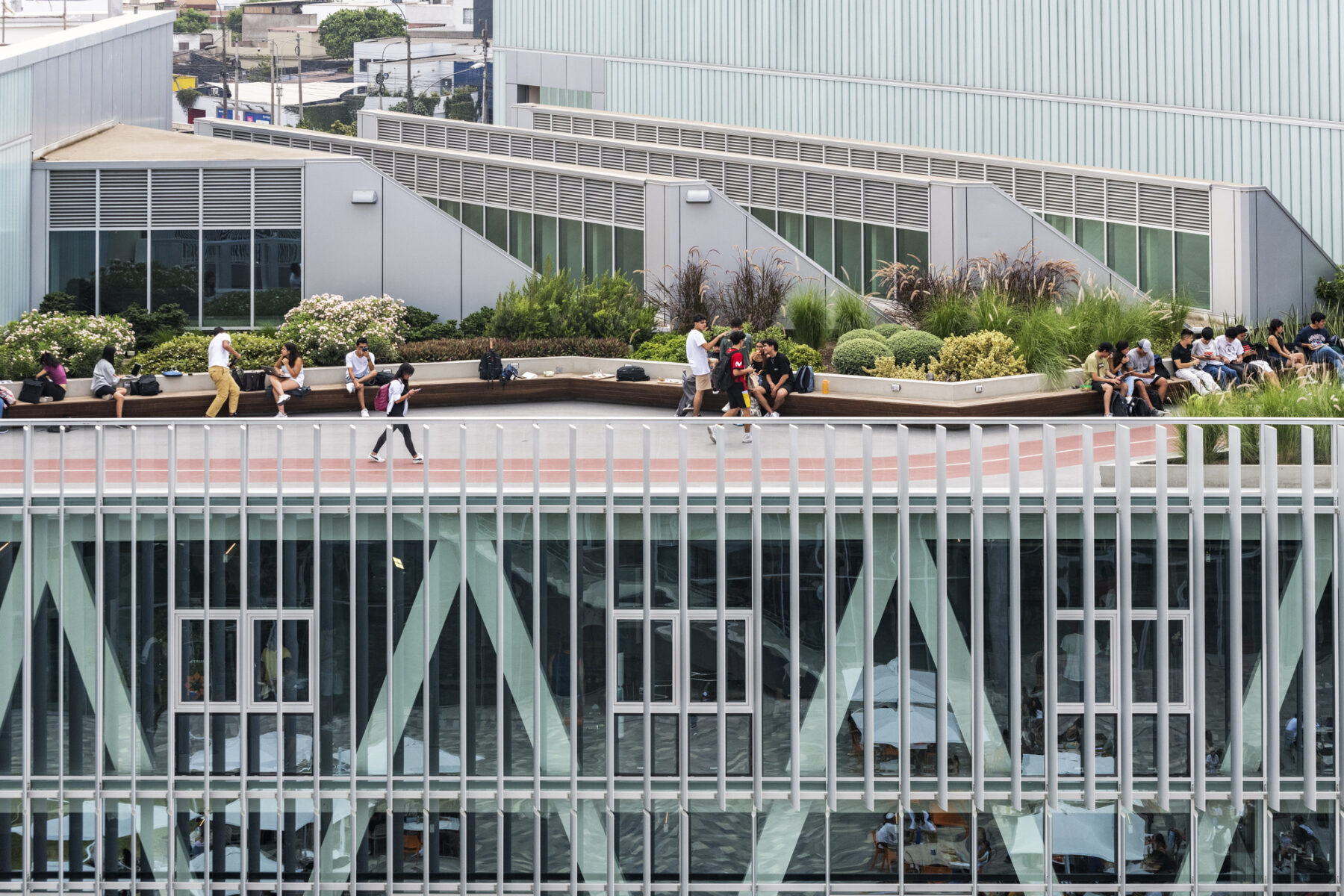 color aerial photo of students walking on an outdoor track on the rooftop of the Wellness Center. Vegetation lines the track and skylights take up the interior of the roof.