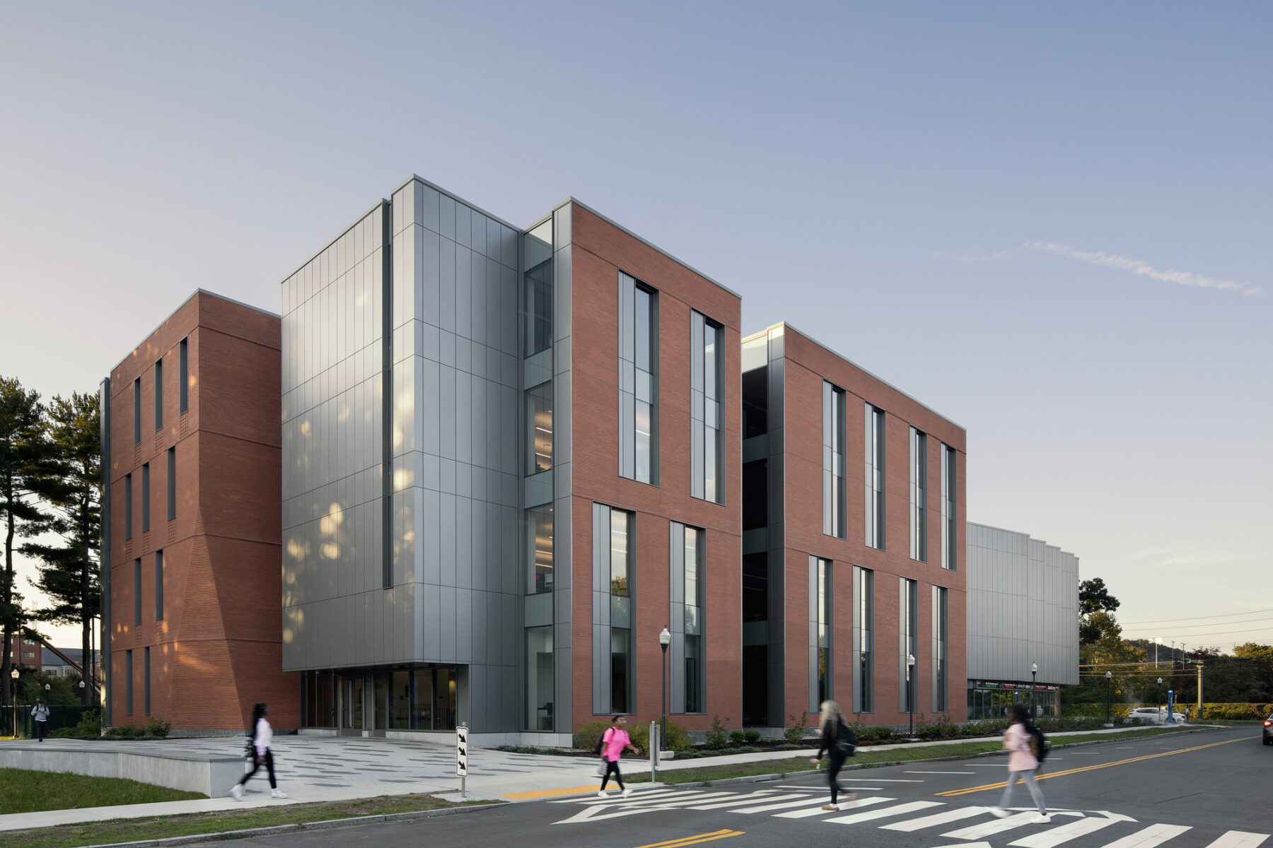 Photo of oblique angle of building showing view down the street and students using the crosswalk in the foreground