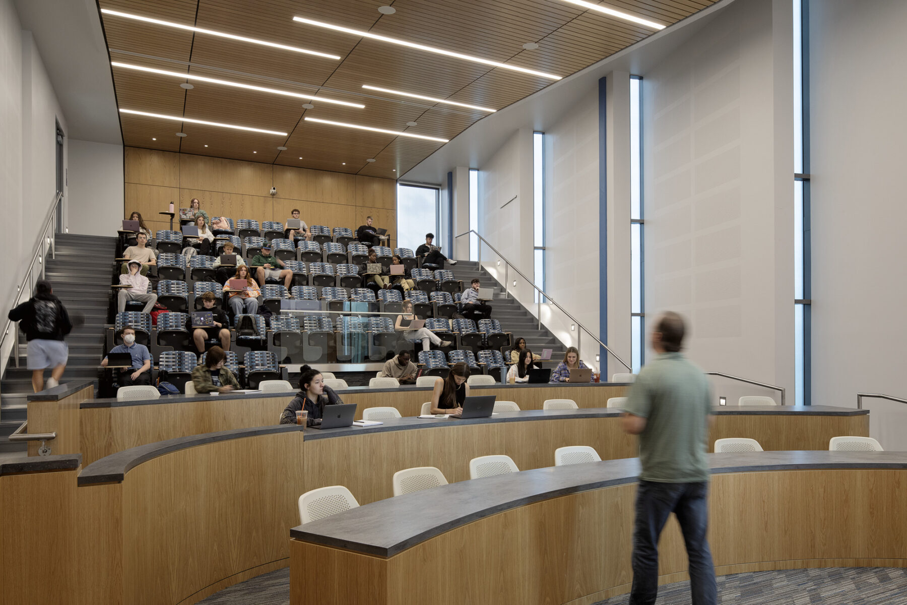 Photo looking up into the double height auditorium with professor teaching in the foreground and students seated and facing forwards