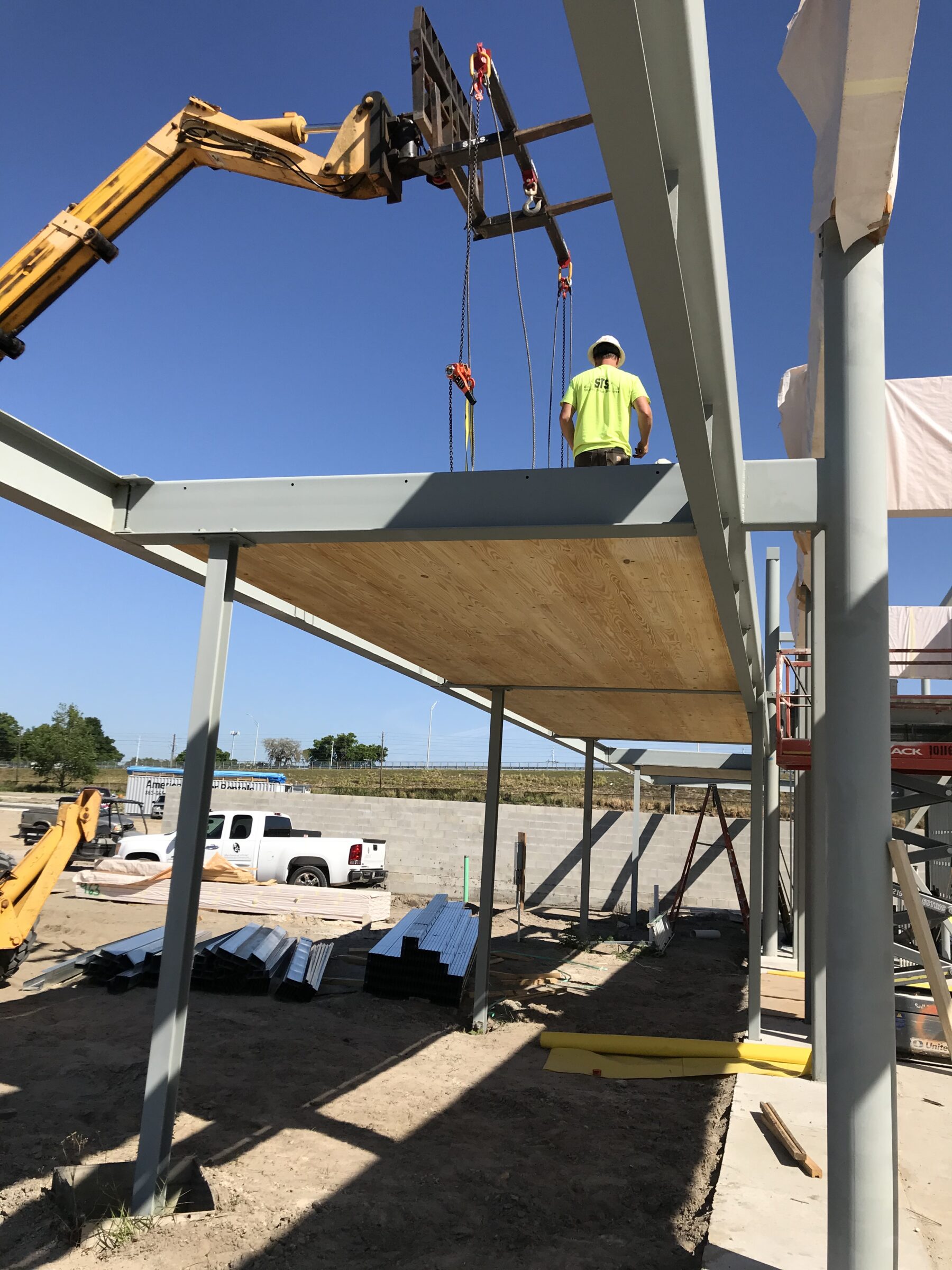 A forklift lowers a CLT panel into place in the wrap-around canopy of the Bonnet Springs Park Event Center during construction