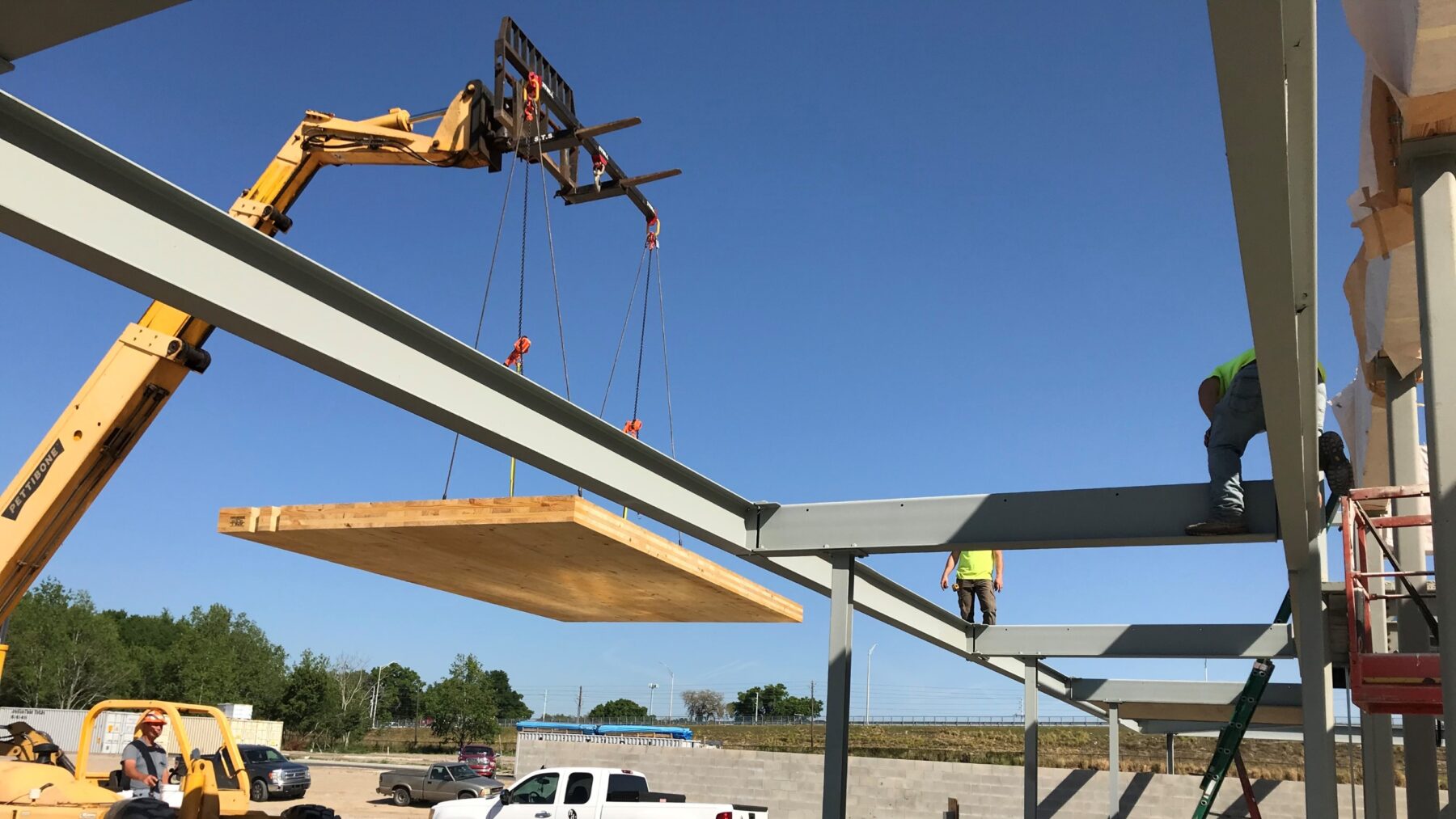 A forklift lifts a CLT panel into place in the wrap-around canopy of the Bonnet Springs Park Event Center during construction