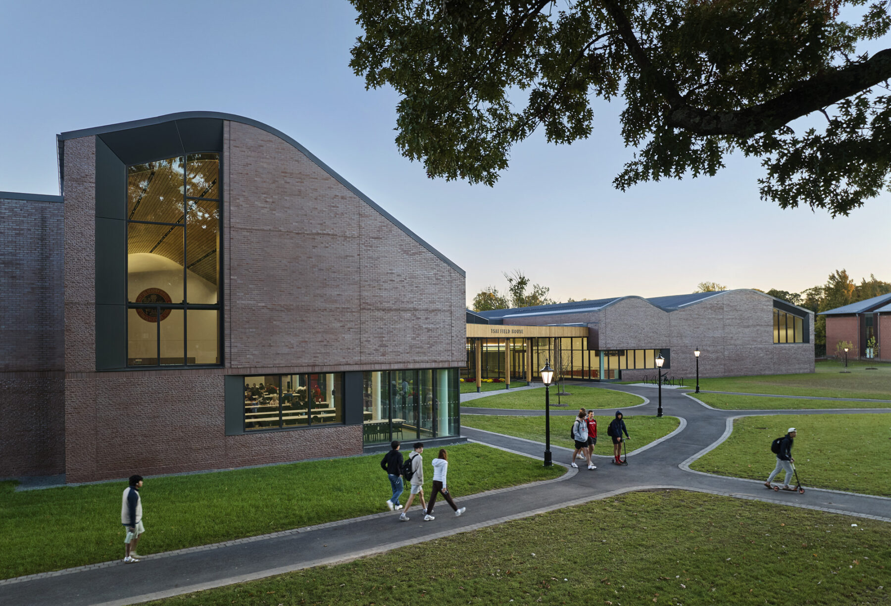 Exterior of building main entry and facade with views inside the windows to the dining hall and gymnasium