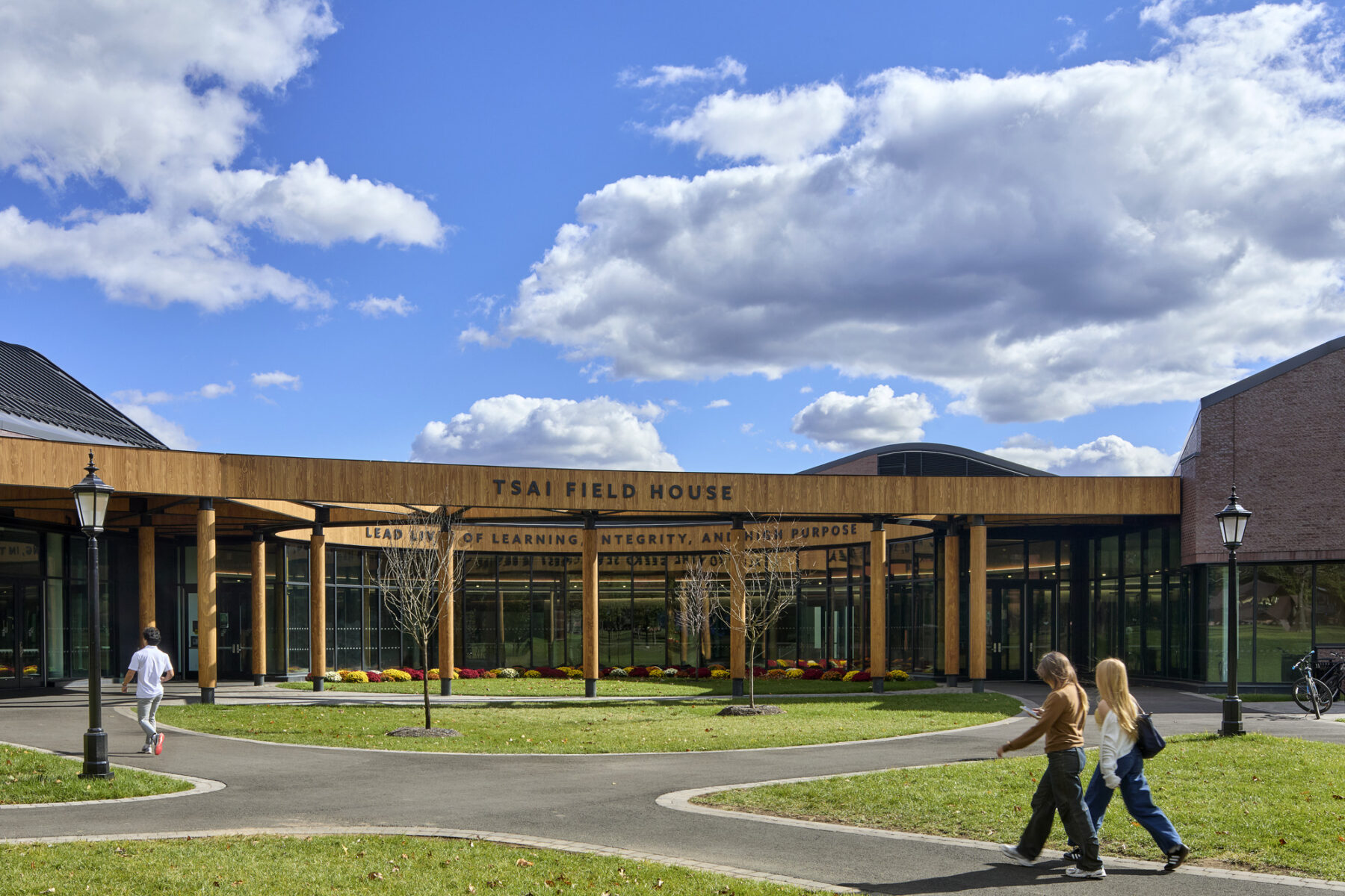 Exterior photo of the oval Harkness Courtyard with it's wooden columns and entry on either side of the oval, connecting to the campus circulation routes