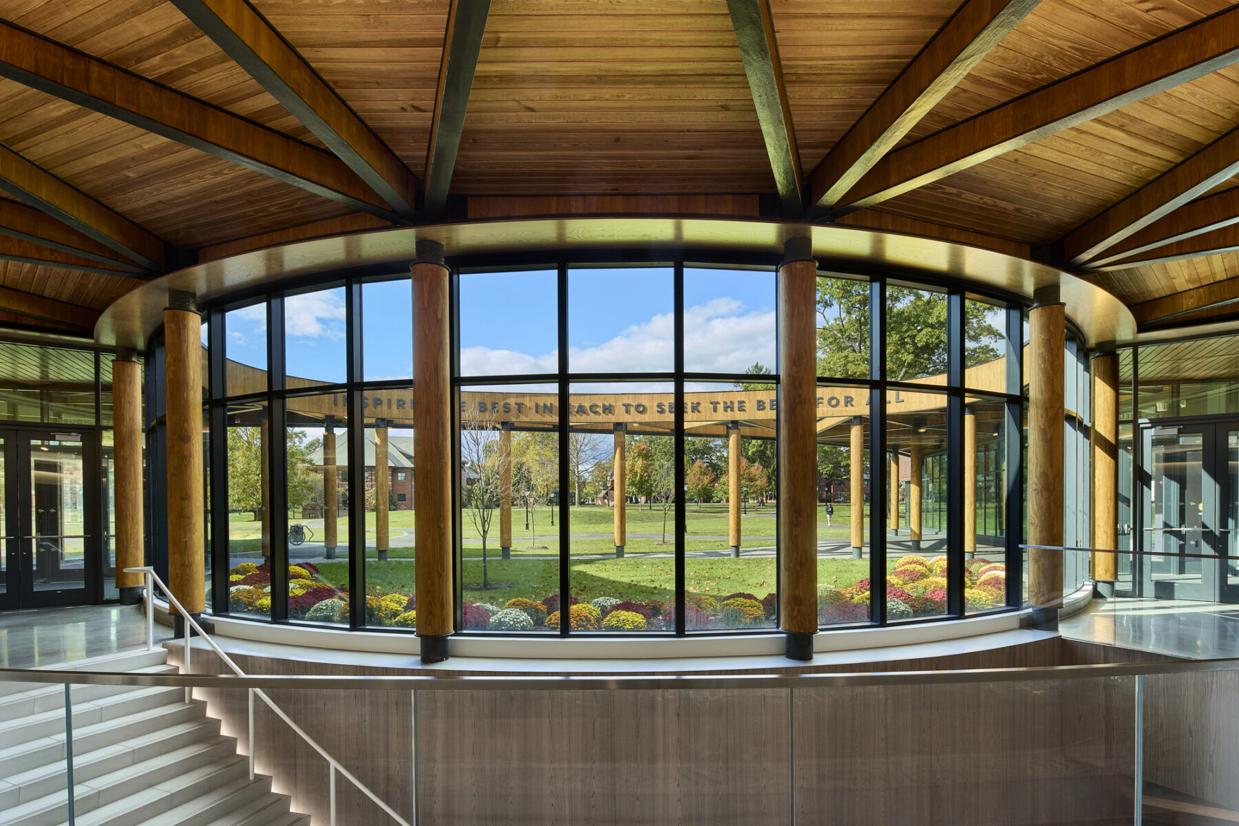 Photo from inside the building lobby, facing out to the rounded Harkness Courtyard, which is open to above and frames the blue sky.