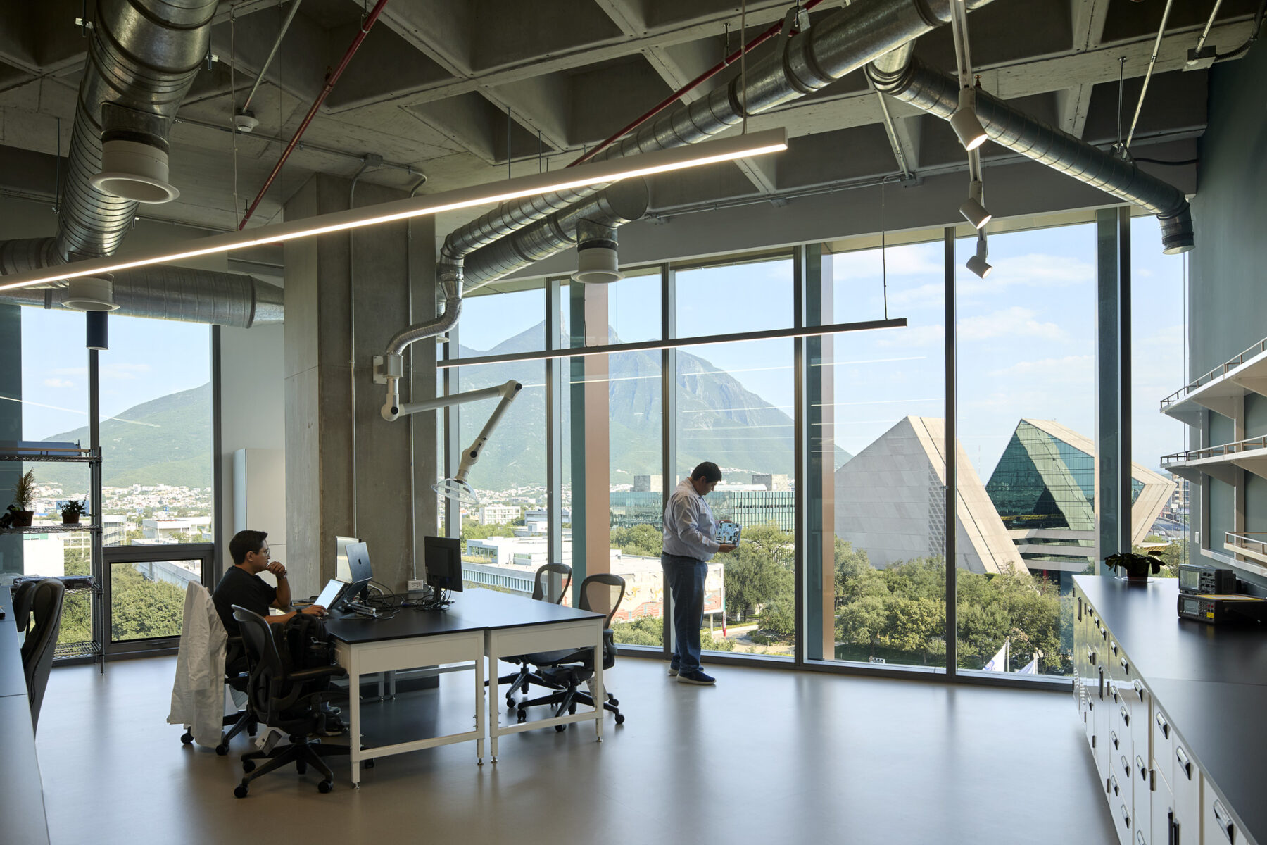 Interior photo of research space with floor to ceiling curtainwall showing views to campus beyond